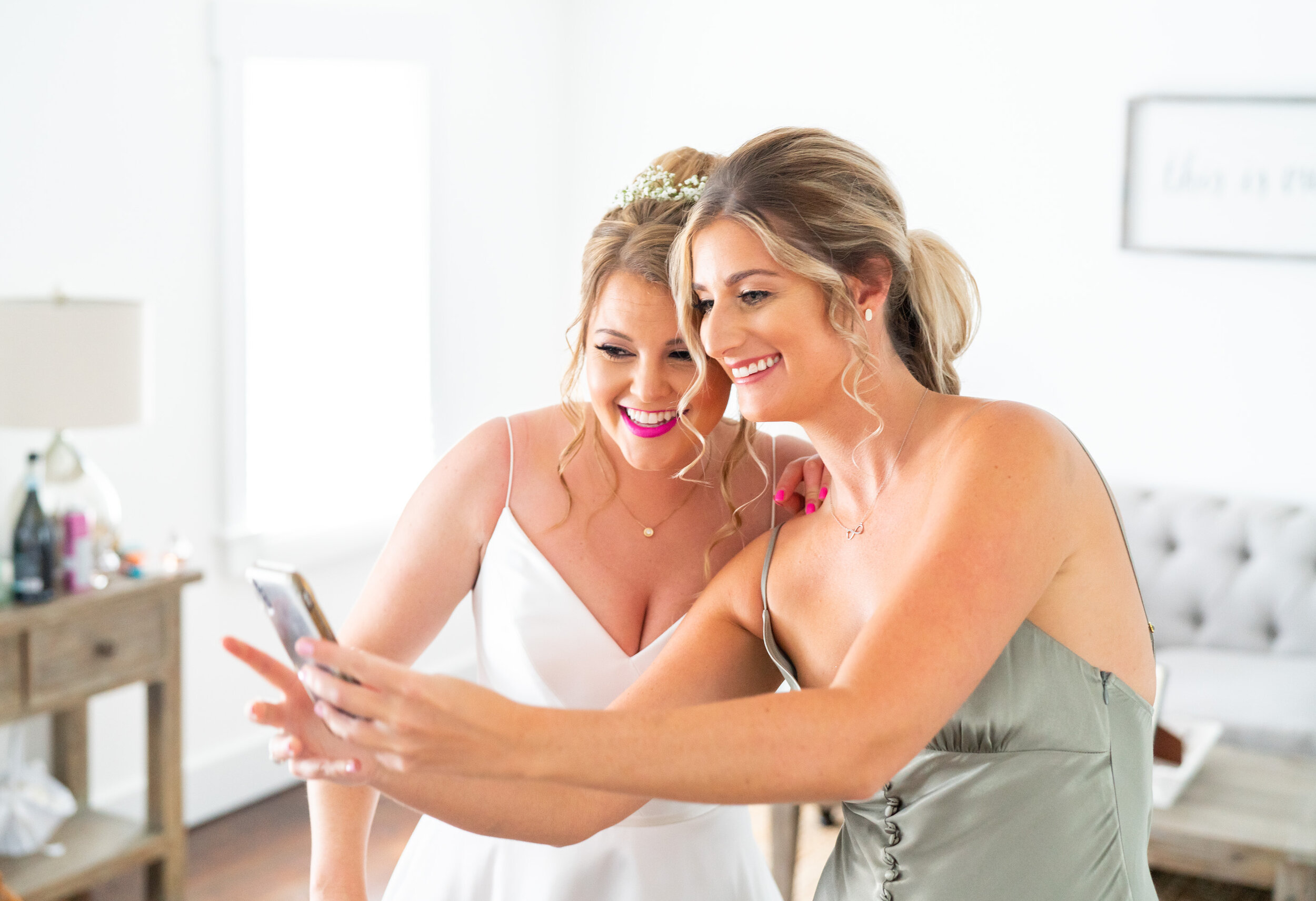 Bride and bridesmaid taking a selfie in sage shona joy dress