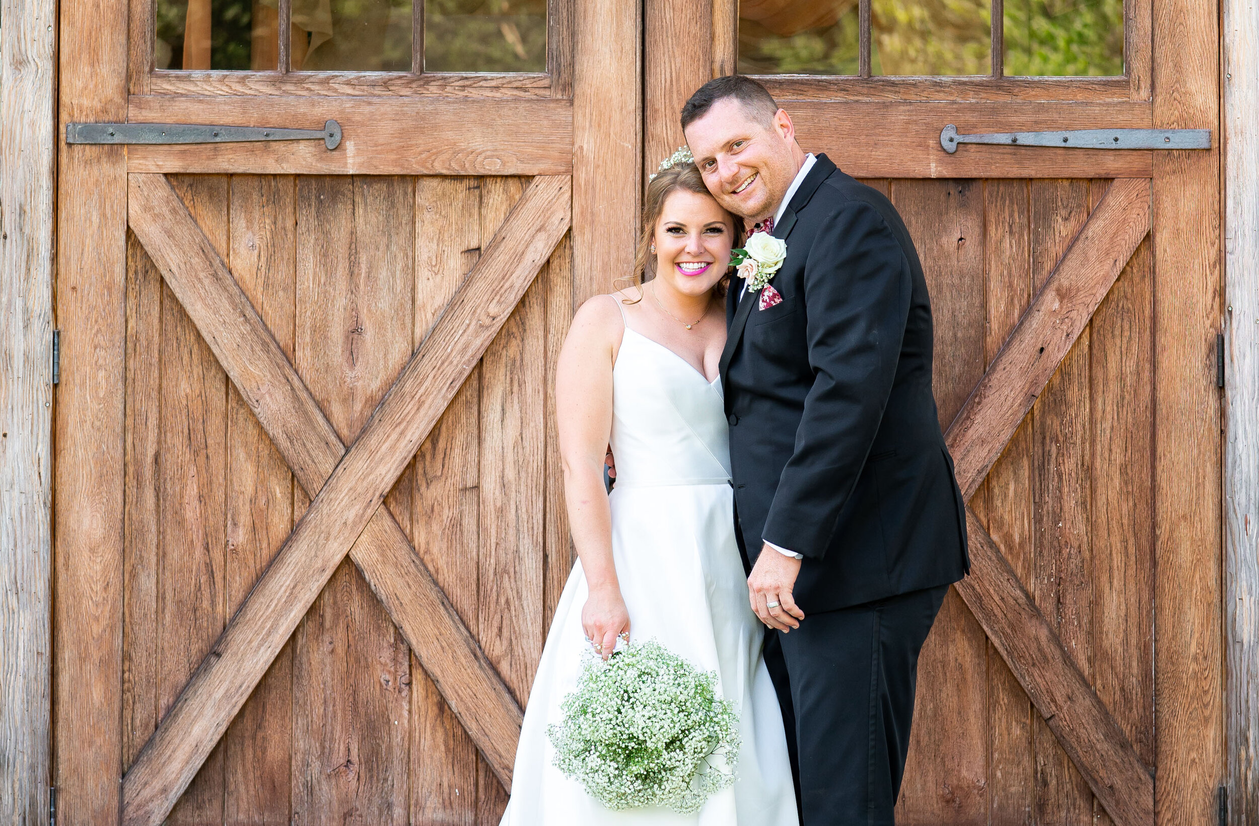 Bride and groom standing in front of barn doors at 48 Fields