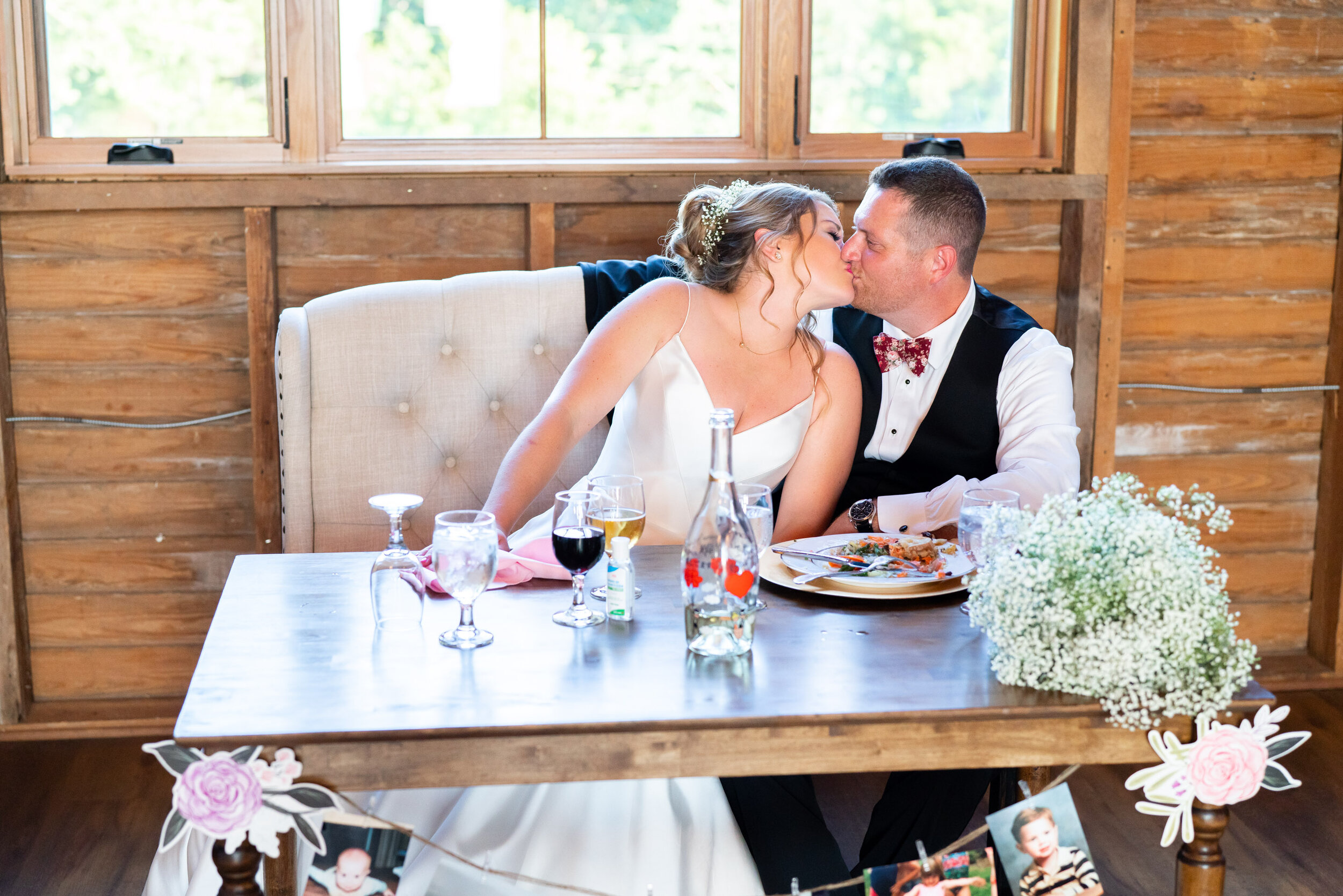 Bride and groom kiss at the sweetheart table in the barn