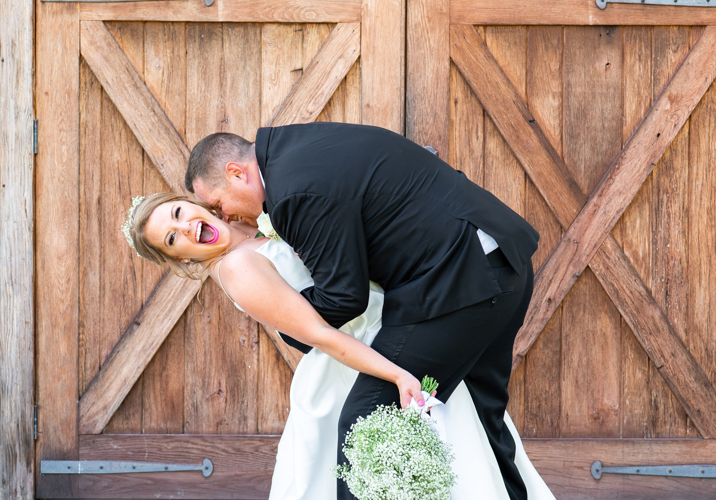 Groom being silly with bride in front of barn doors at 48 Fields
