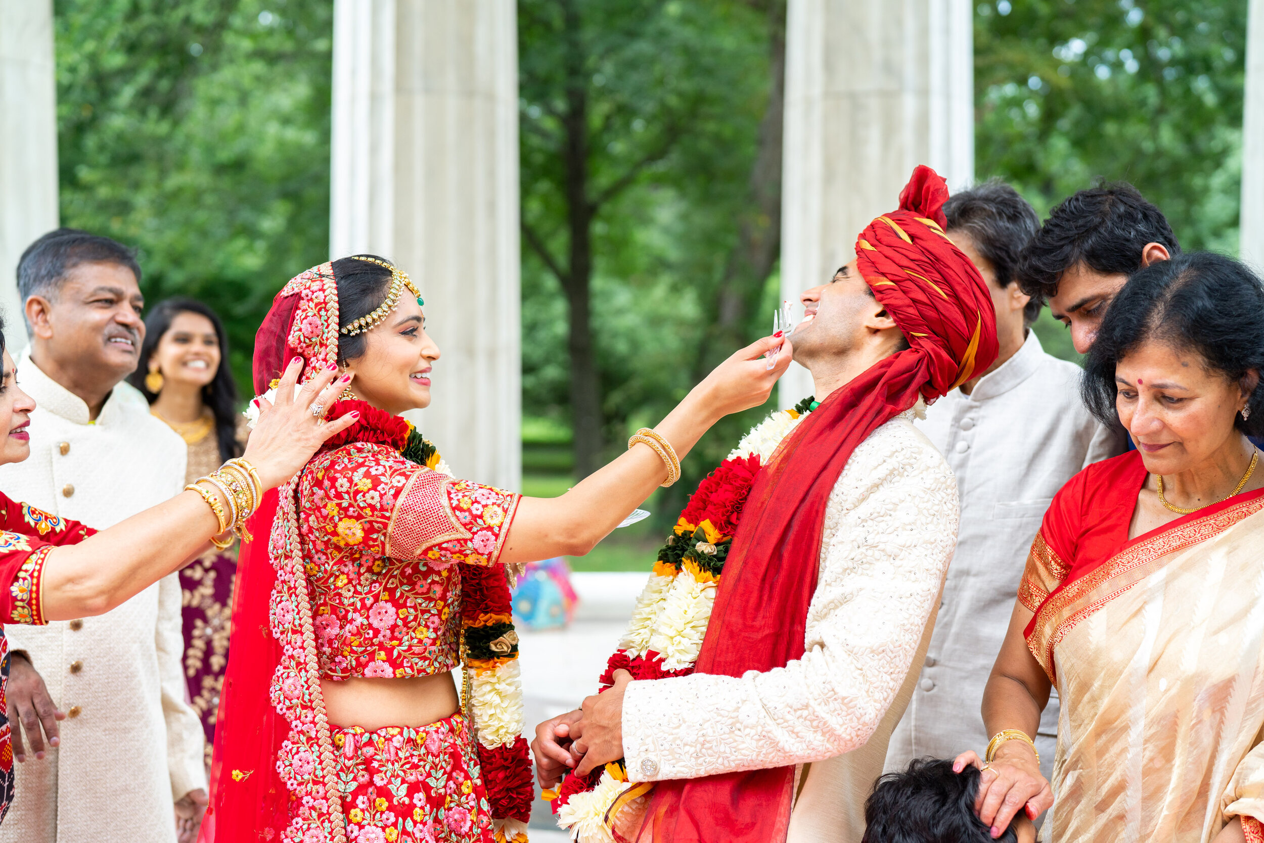 Indian bride wiping cake on groom at DC War Memorial columns