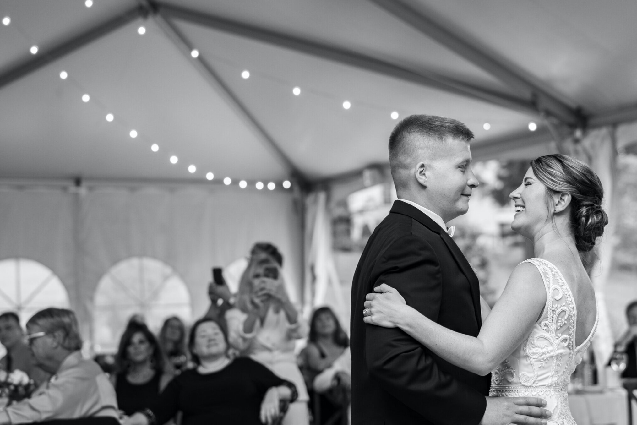 Black and white image with twinkle lights of bride and groom first dance