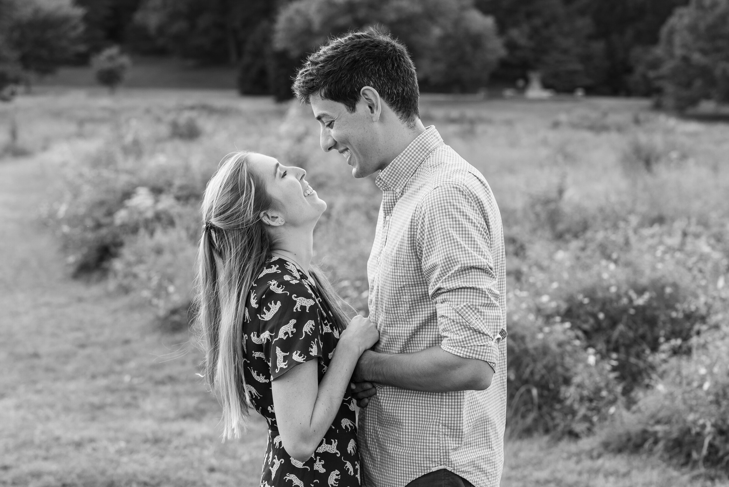 Black and white image of couple hugging and smiling in field