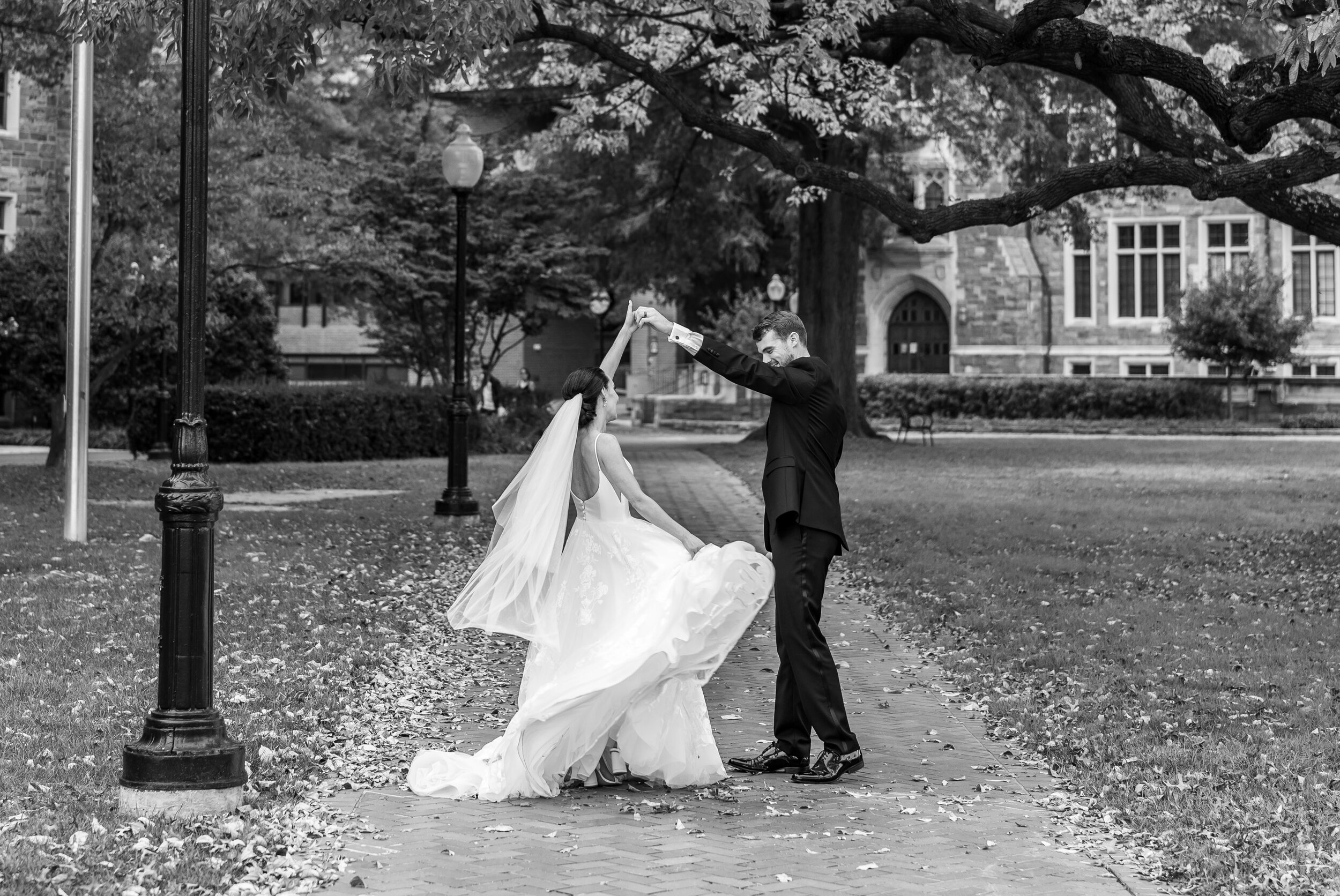 Groom twirling bride on sidewalks at Georgetown University