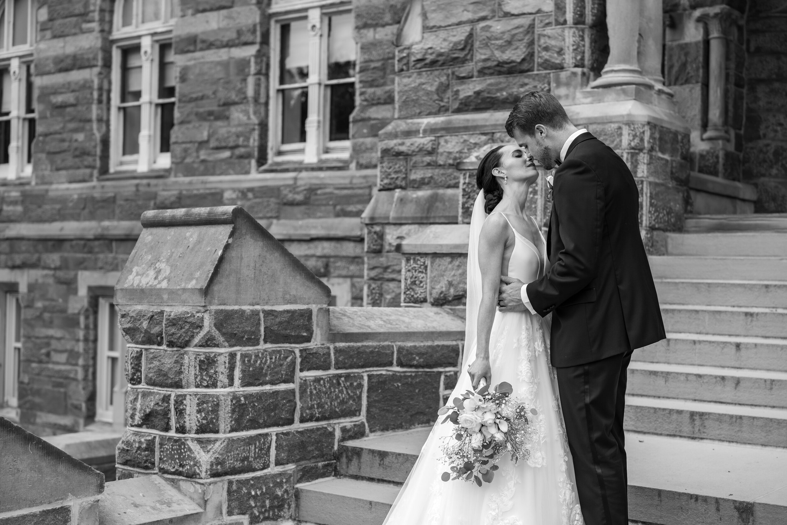 Black and white image of bride and groom kissing on steps of Georgetown University