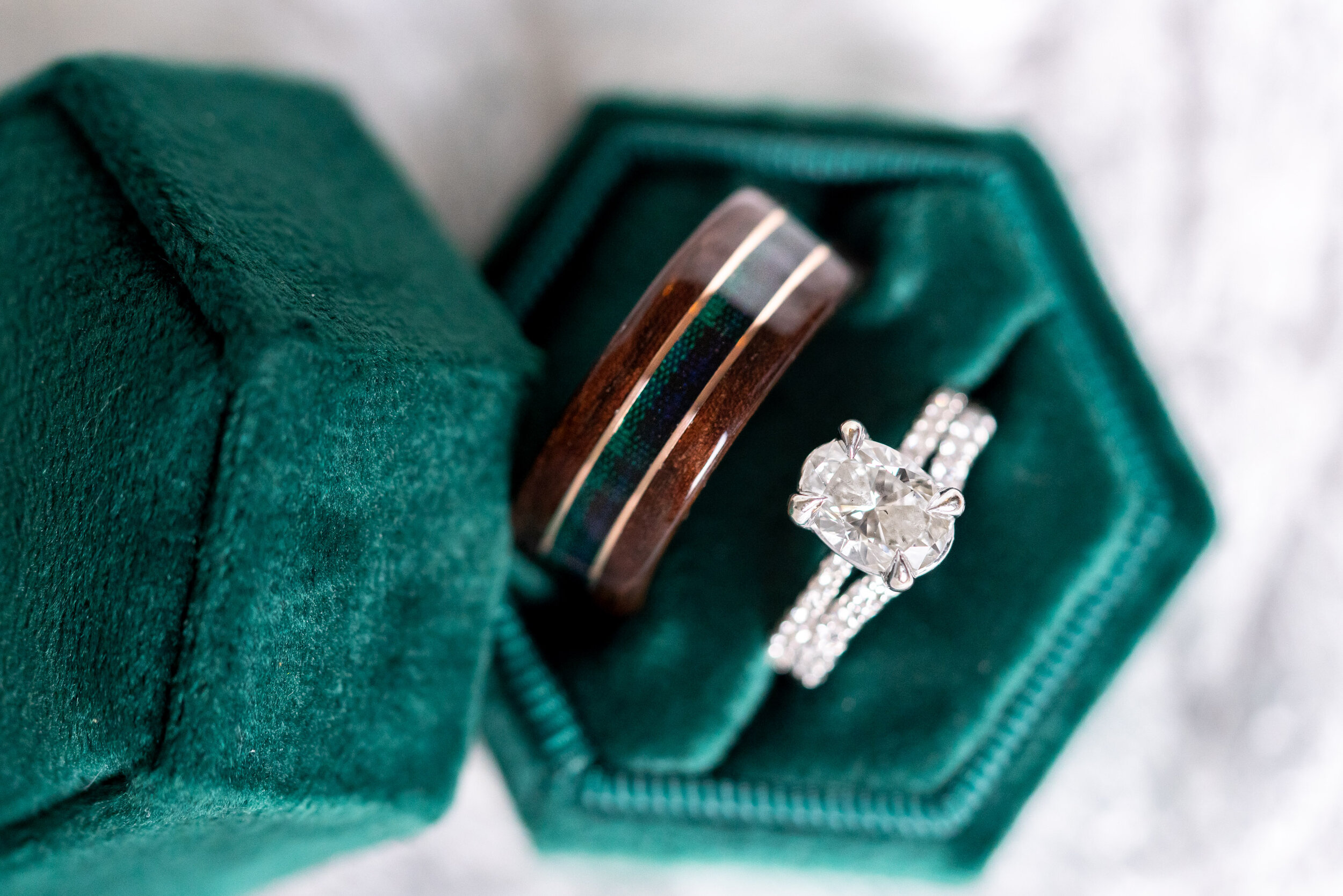 Oval engagement ring, diamond band, and wooden band in emerald velvet box