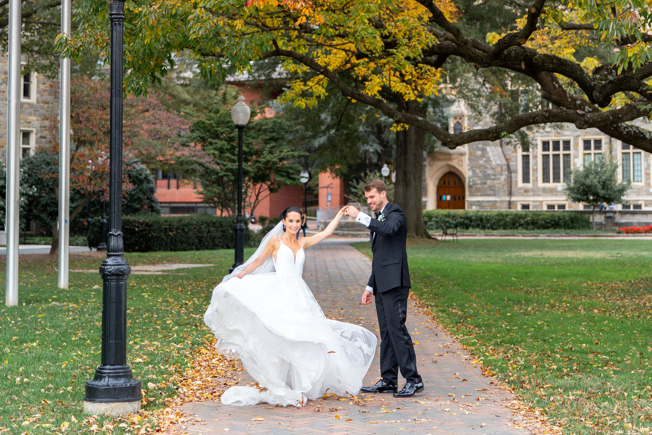 Bride twirling under fall trees on Georgetown University grounds