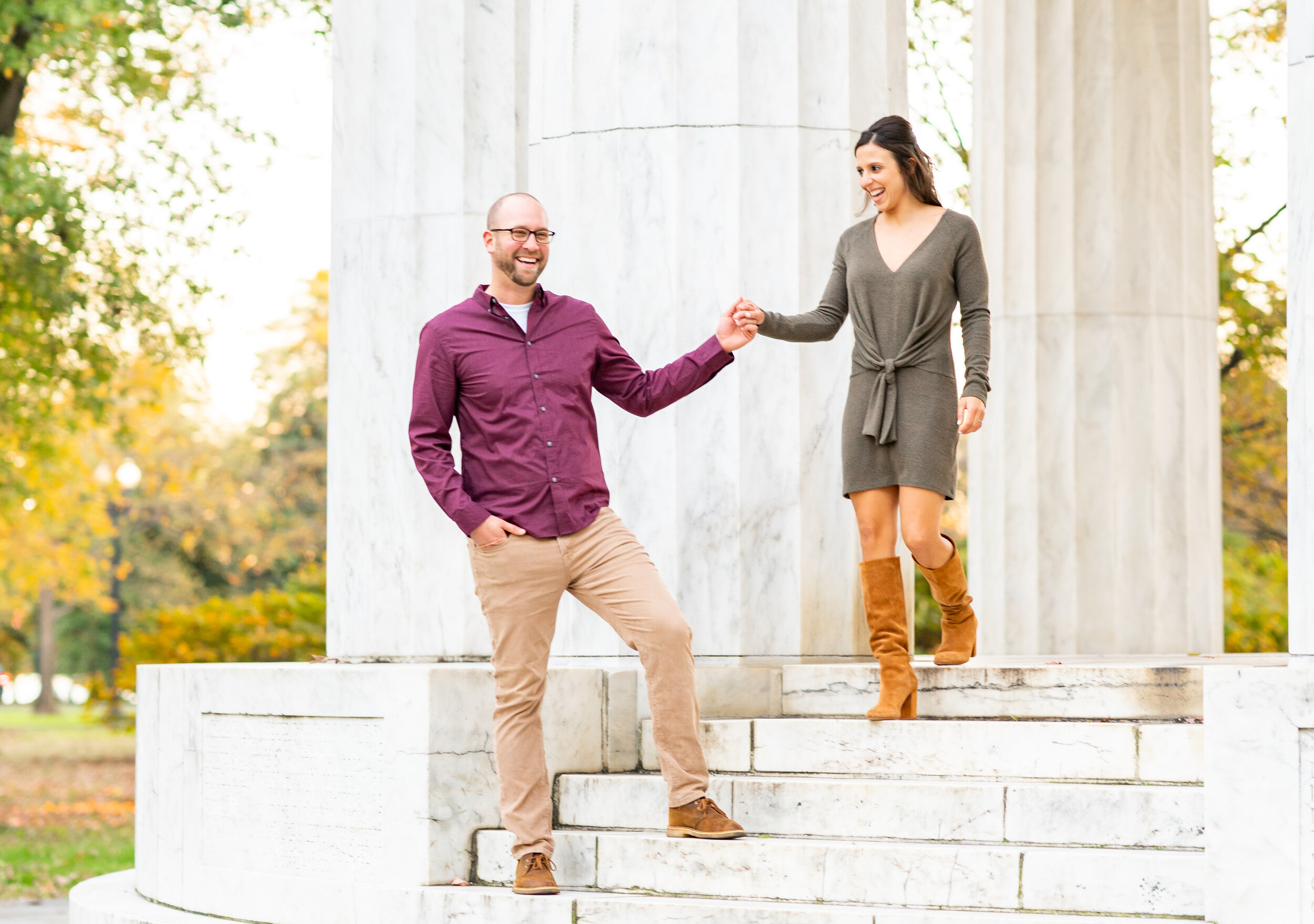 Groom helping bride down stairs engagement session at DC War Memorial