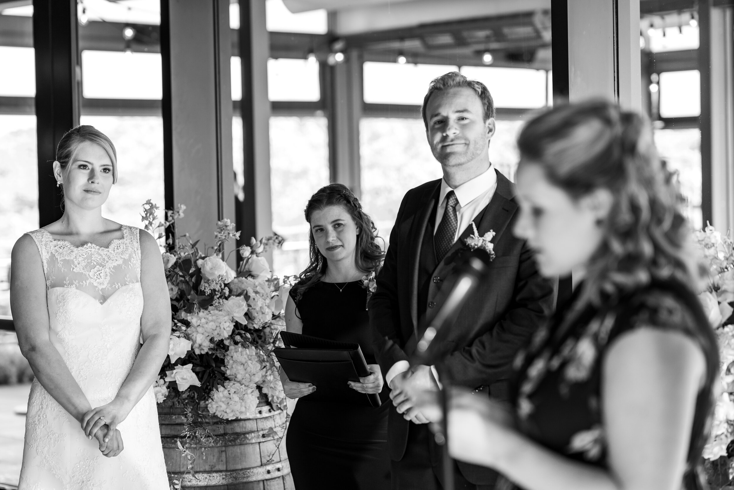 Bride and groom looking on as a guest reads