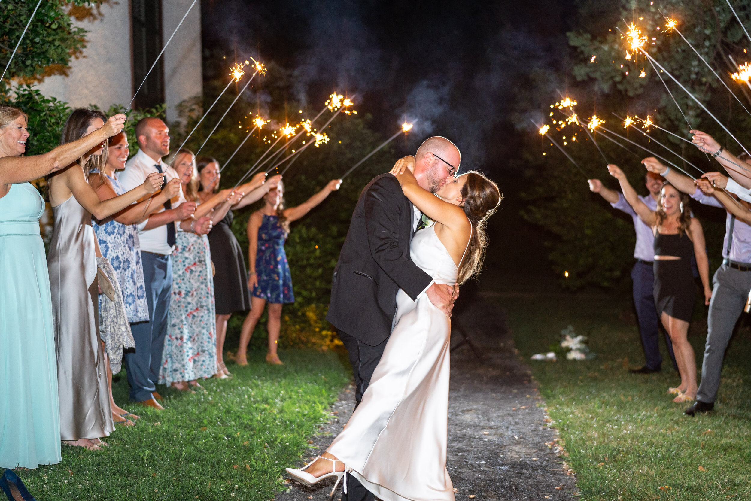 Bride and groom kiss under sparkler exit at fun wedding at Lincolns Cottage 