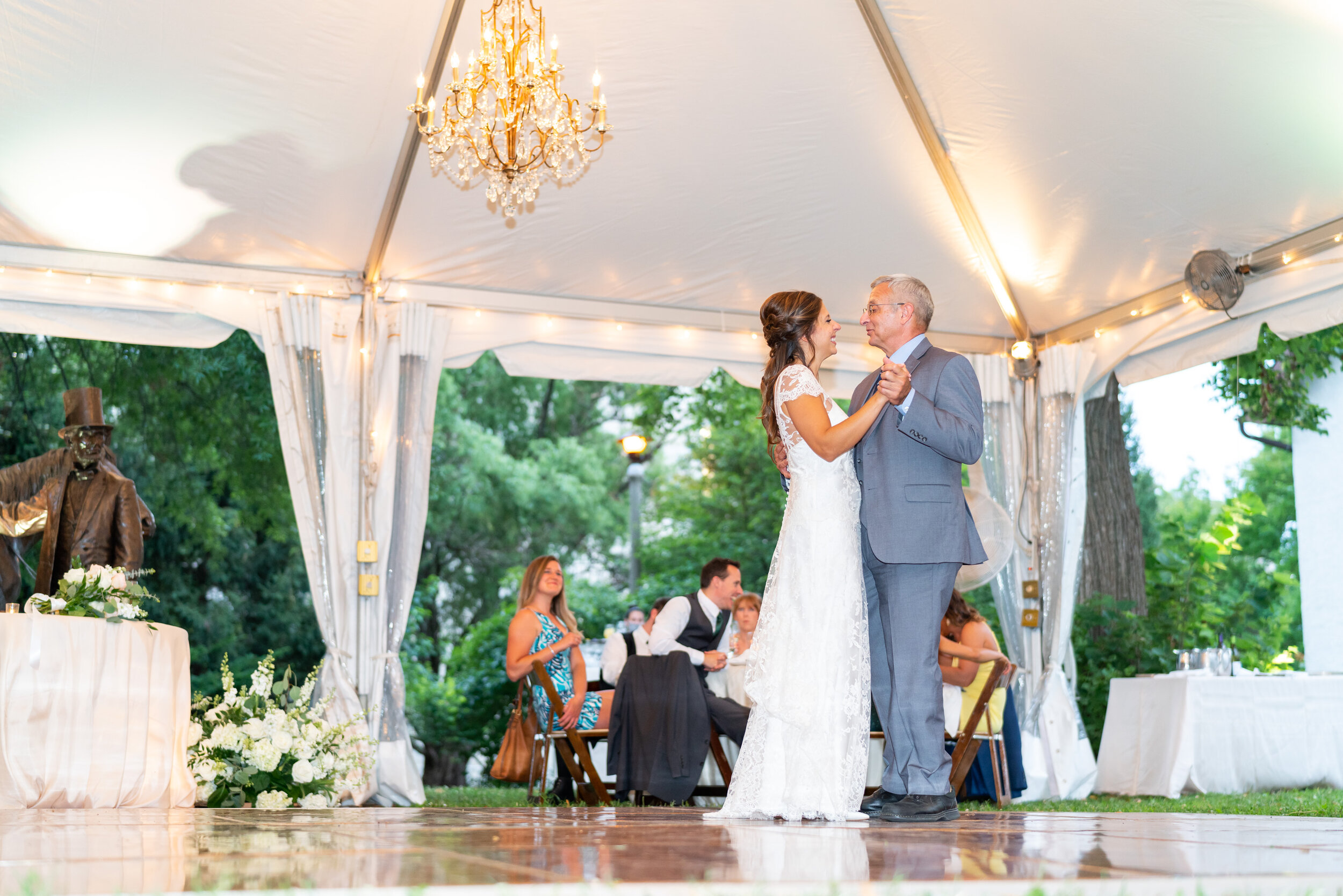 Bride and her dad share father daughter dance under white tent with chandeliers at Lincolns Cottage
