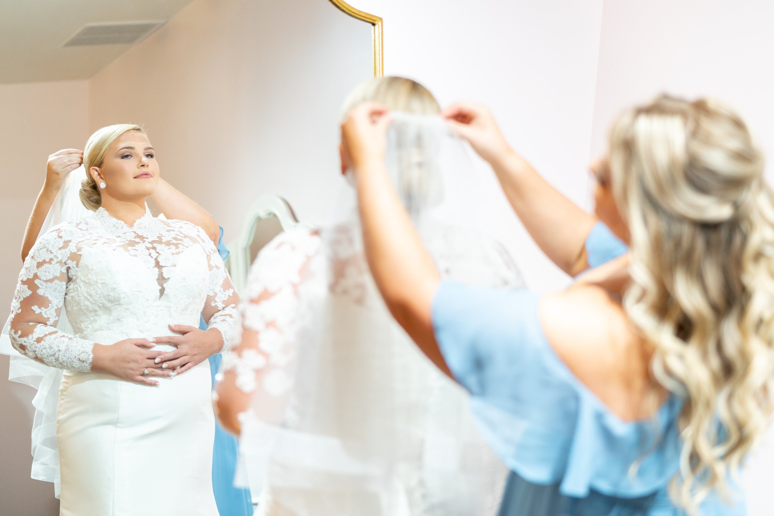 Bride looks at herself in the mirror at Running Hare bridal suite
