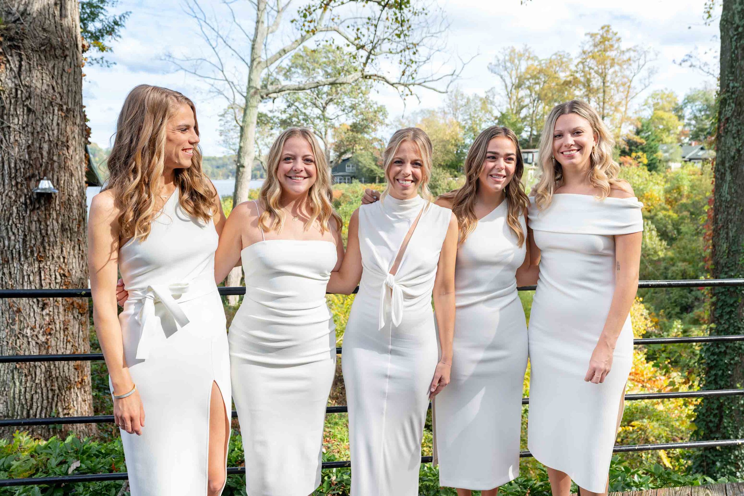 Bride and bridesmaid all wear white dresses at Sherwood Forest in Maryland