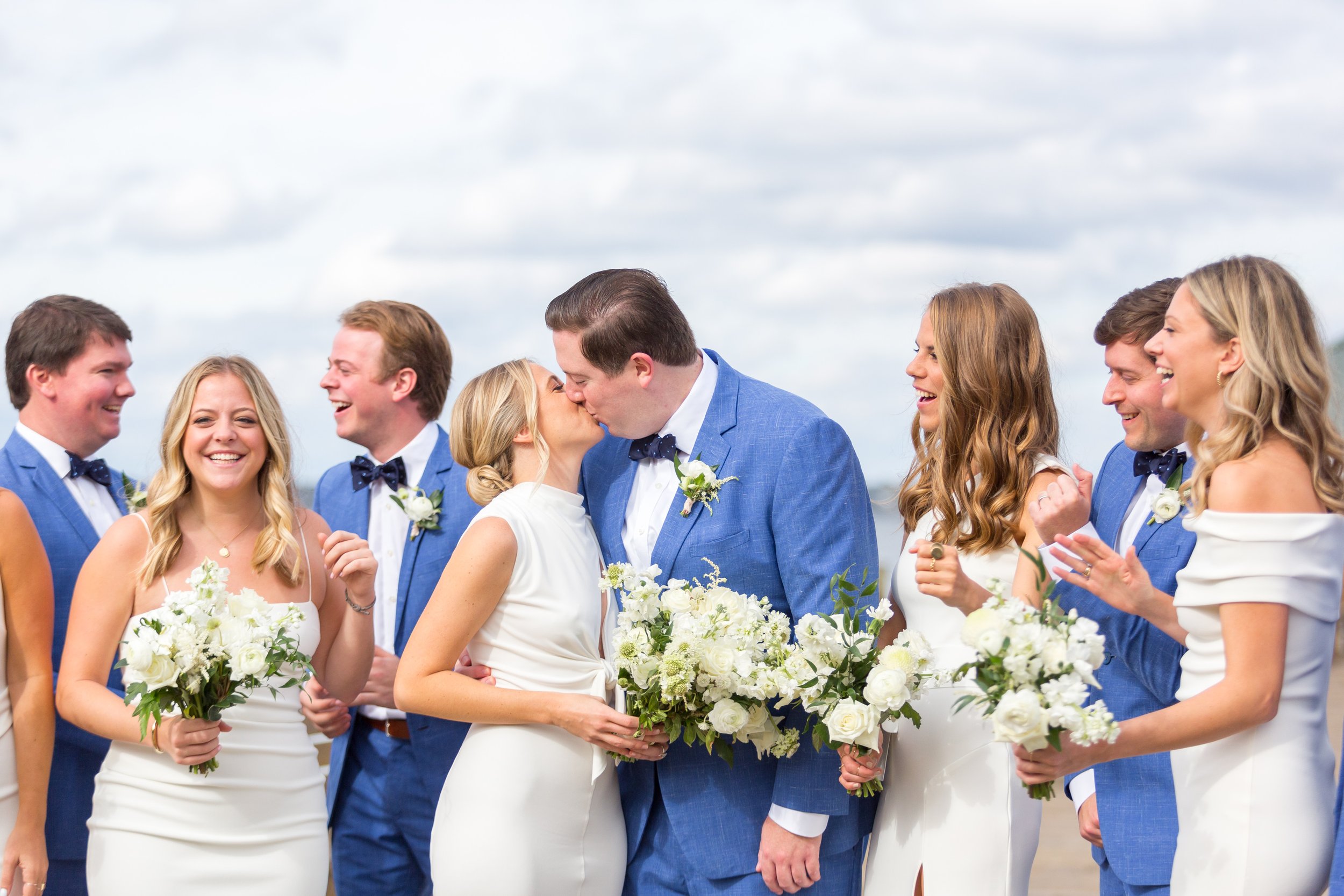 Bride and groom kiss while wedding party cheers