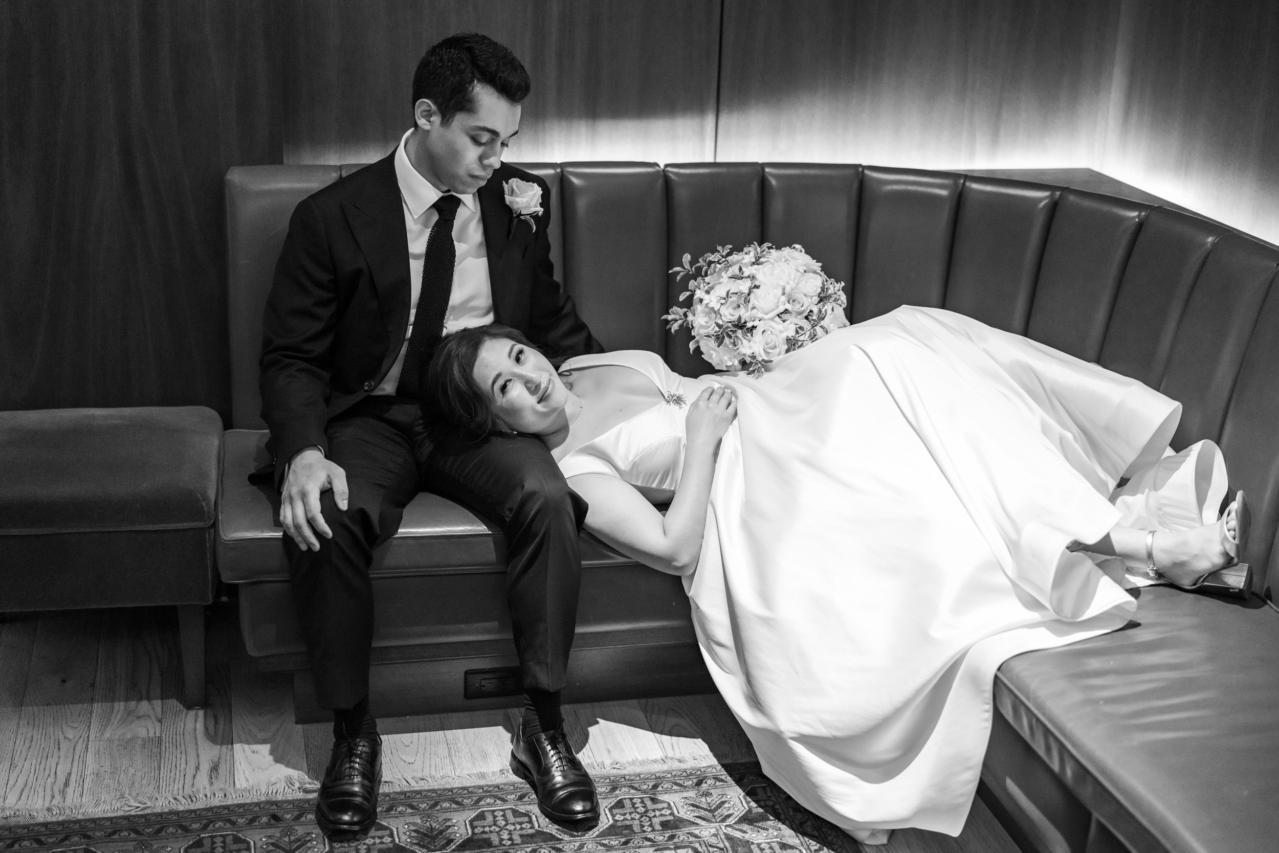Romantic black and white portrait of bride laying in grooms lap