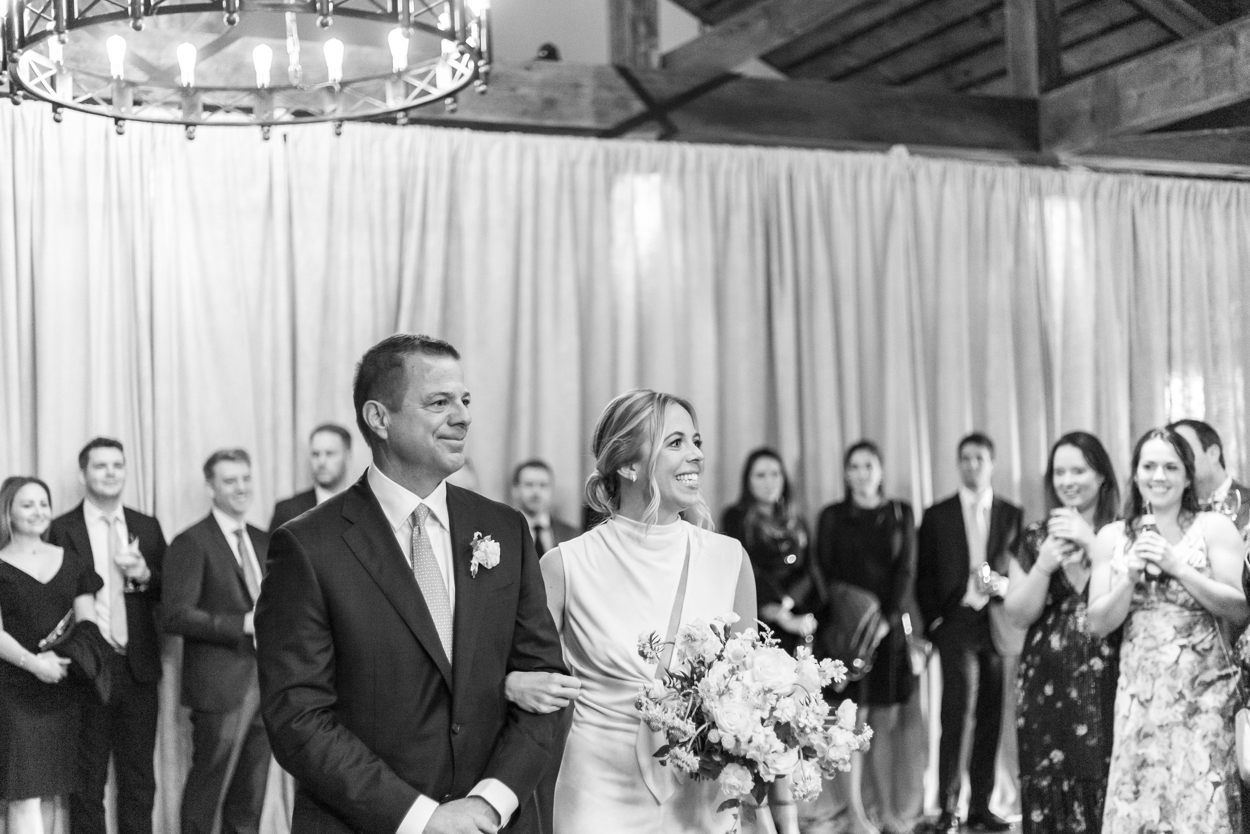 Bride walks down the aisle in black and white photo