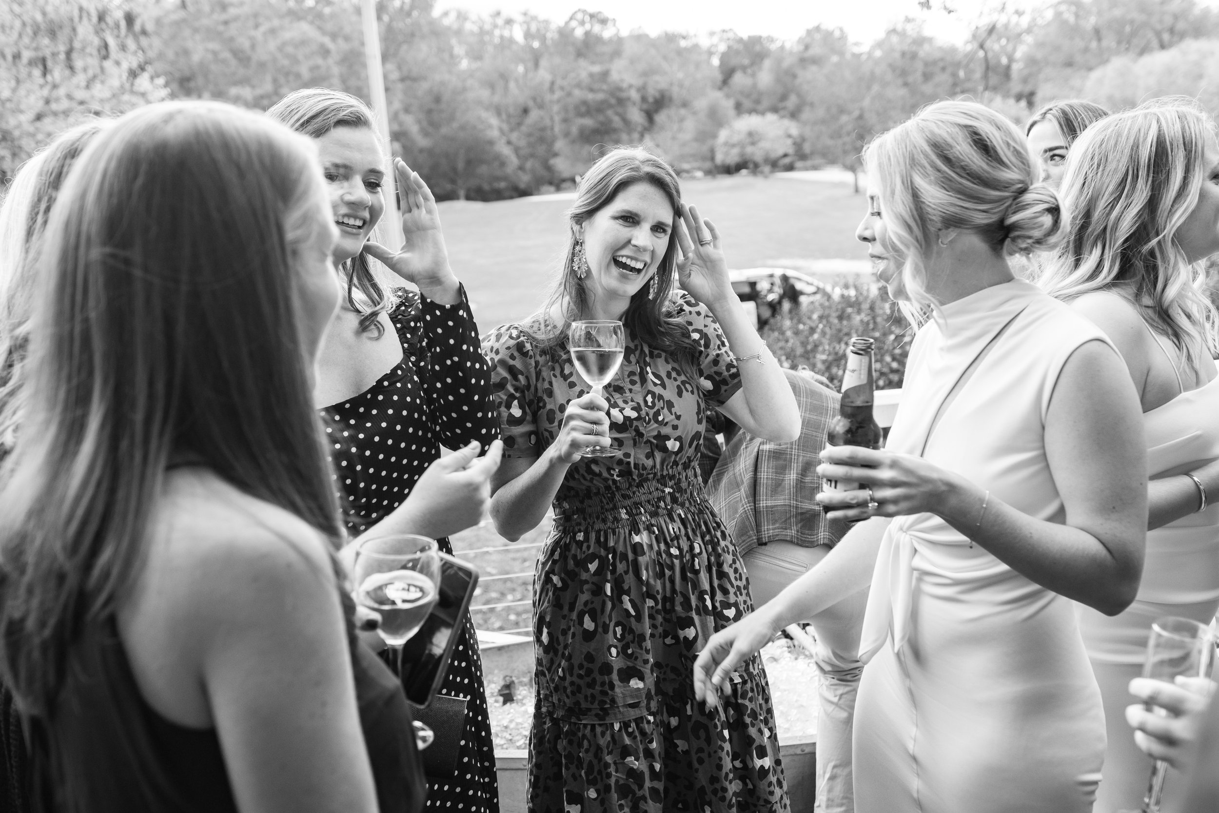 Black and white image of girls chatting with bride during cocktail hour outdoors