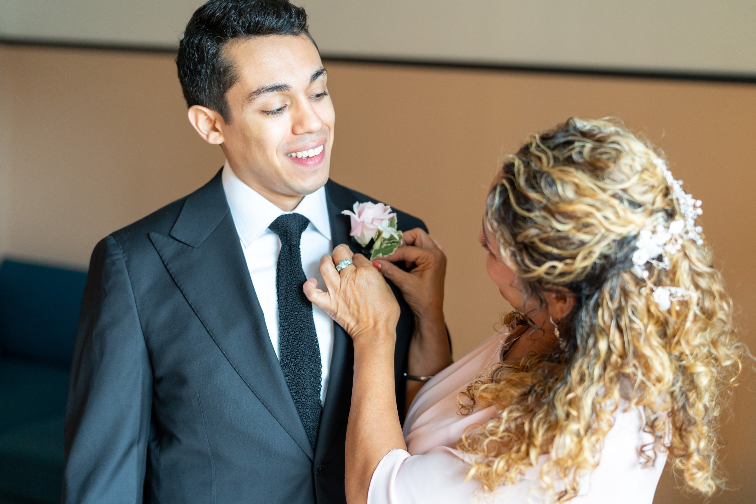 Grooms mom pinning boutonniere on her son at fun wedding