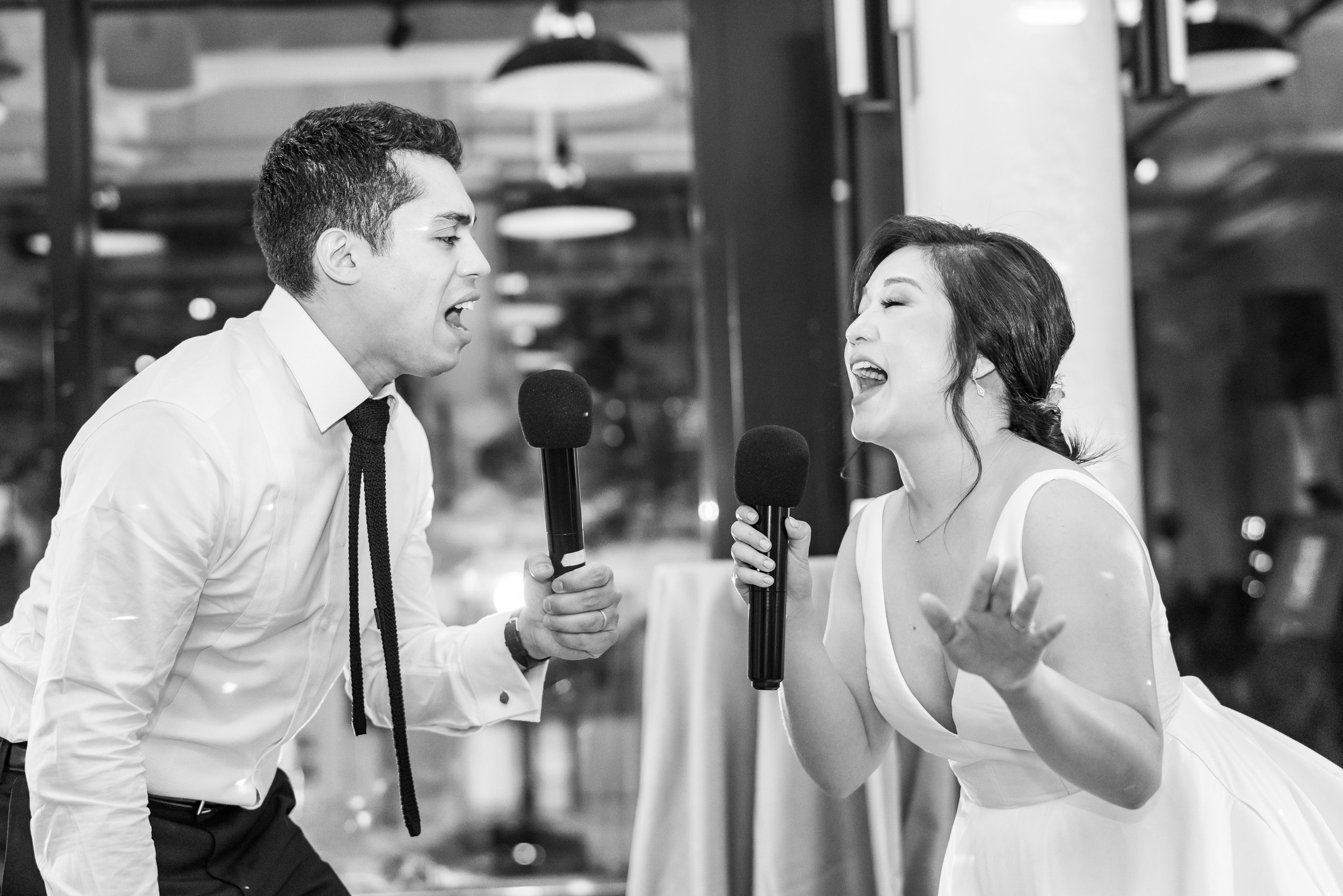 Bride and groom sing to each other during karaoke at their fun wedding