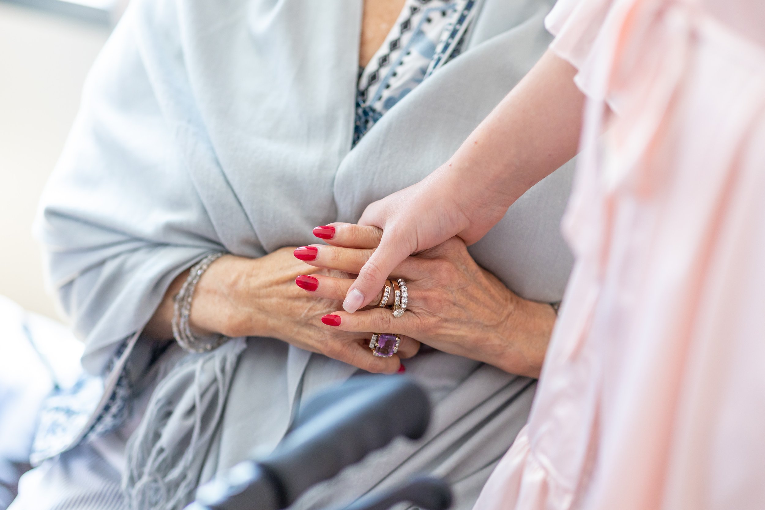 Close up photo of bride holding her grandma's hand while getting ready at the Watermark Hotel