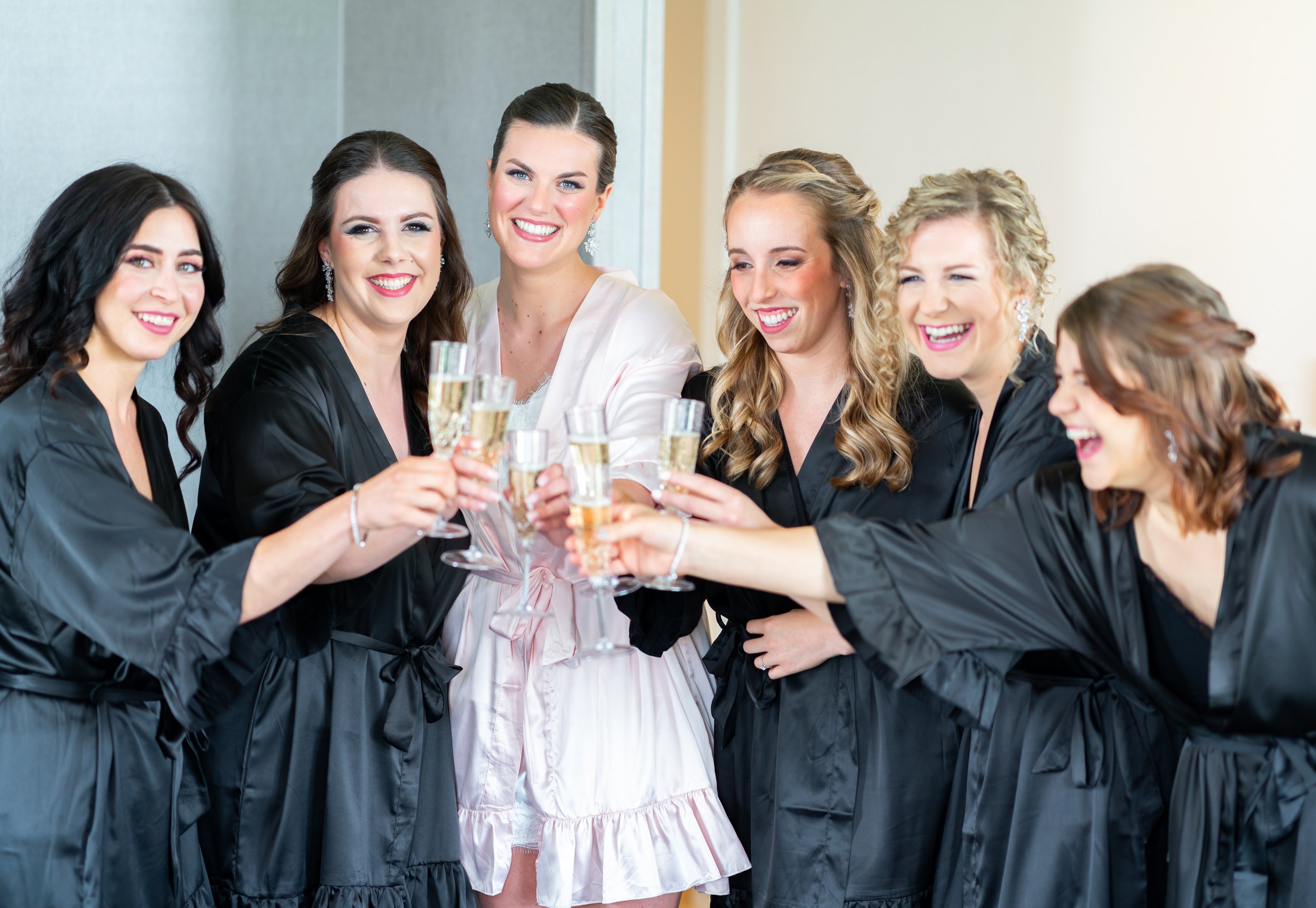 Bride and bridesmaids in matching robes toasting champagne