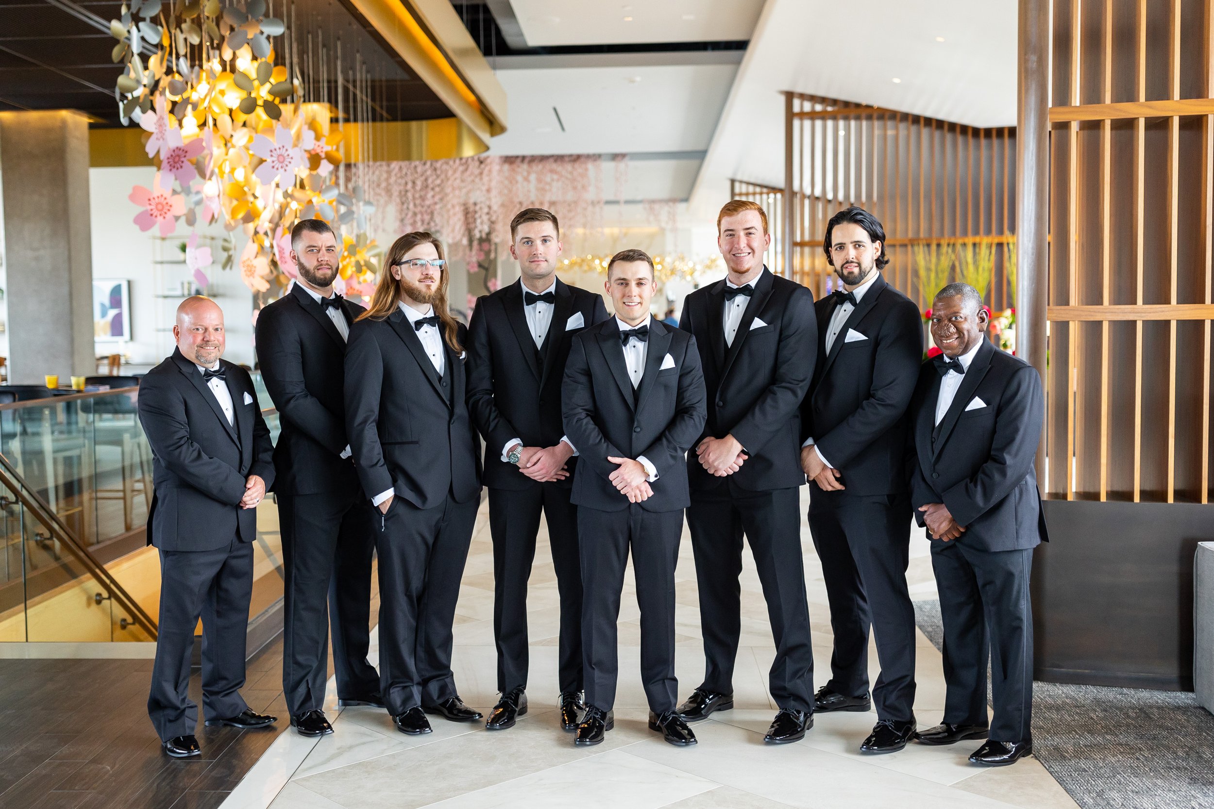 Groom and groomsmen pose for wedding portraits in lobby at Watermark Hotel