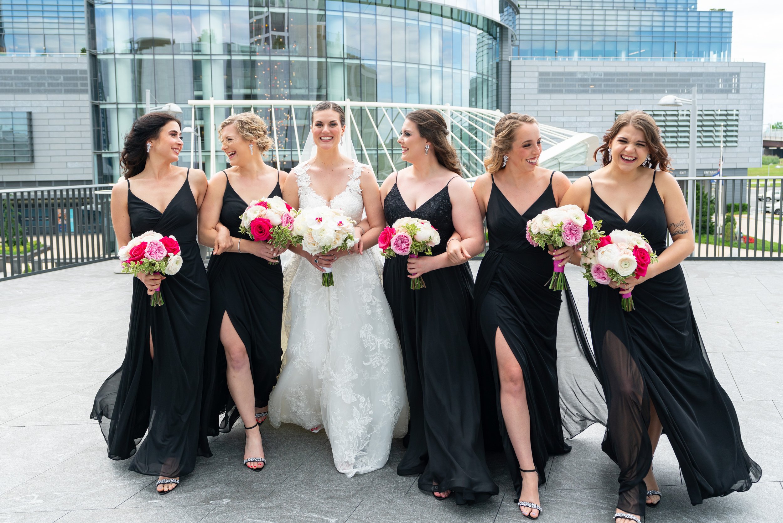 Bride and bridesmaids in black and white gowns on cocktail hour balcony at Capital One Hall