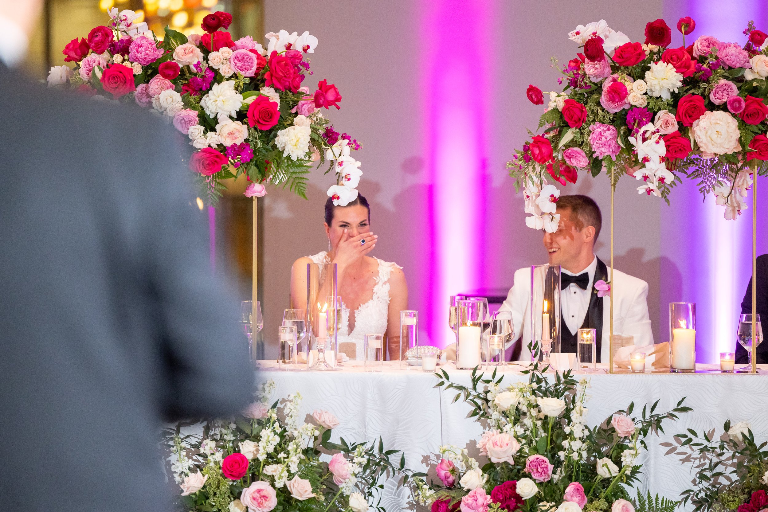 Bride and groom laugh in reaction to a toast during the reception