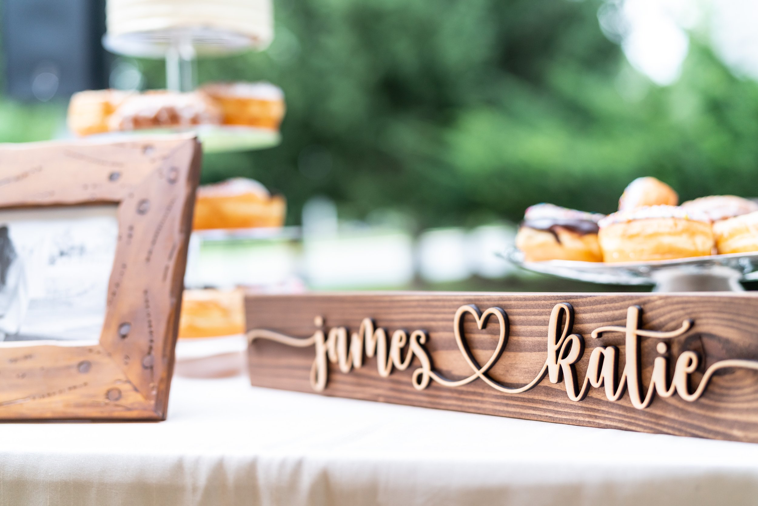 Custom signage with bride and grooms names on the cake donut table