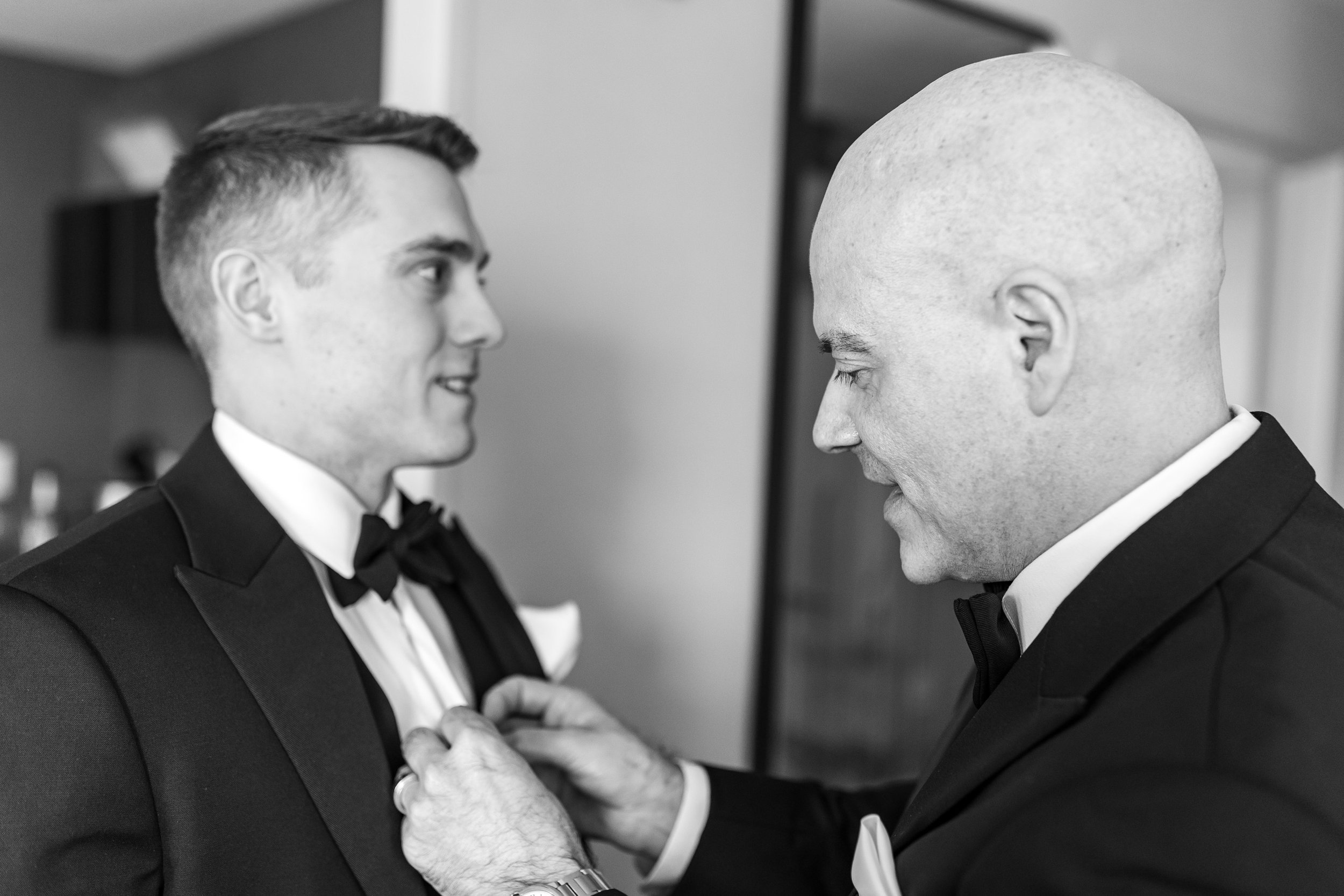 Candid fun photography of bride's father buttoning up the groom