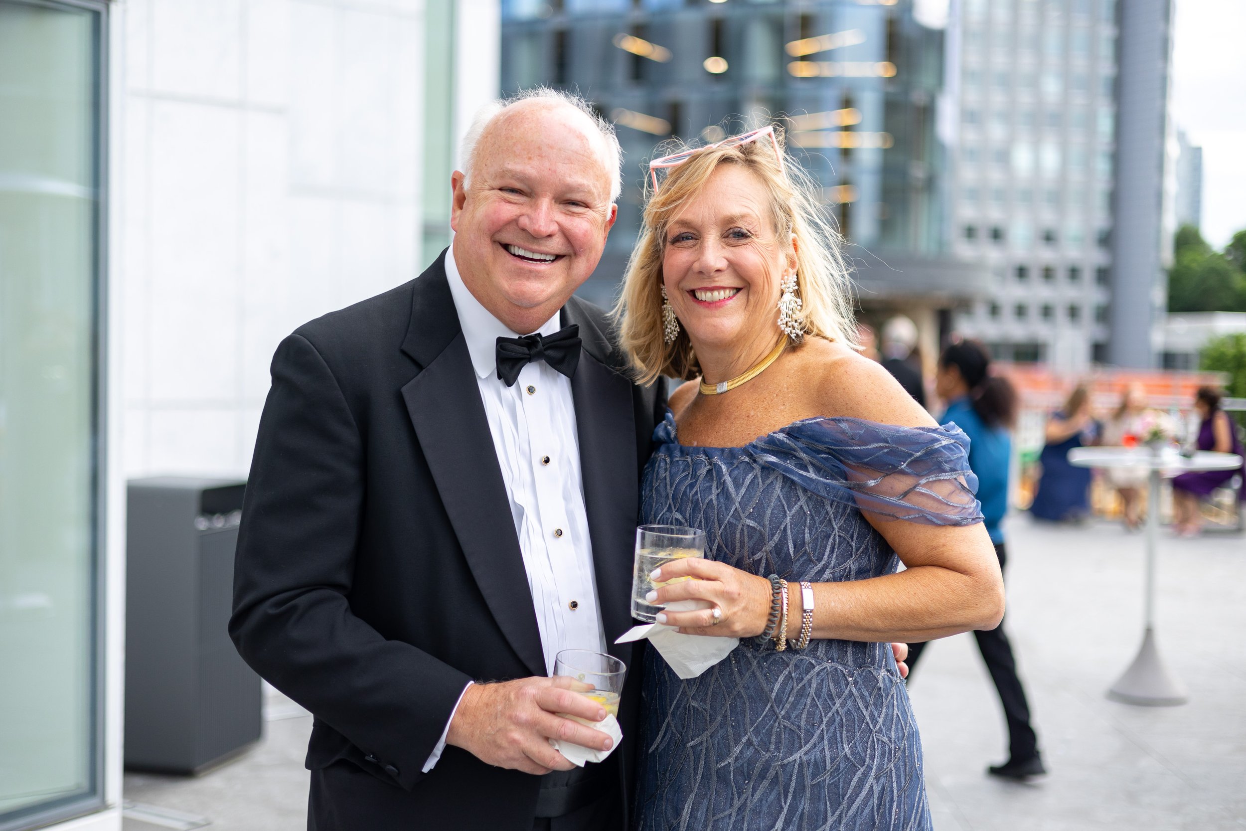 Husband in a tux and wife in a gown enjoy drinks on the balcony at Capital One Hall