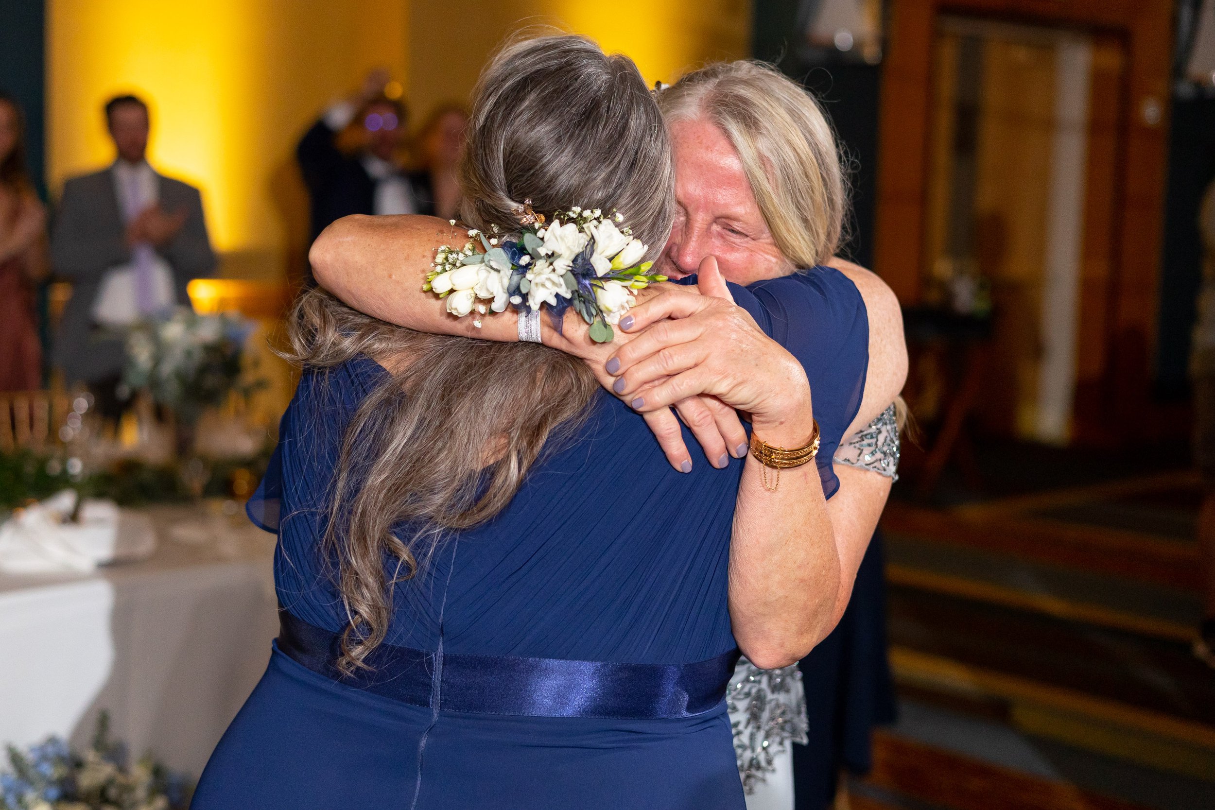 Mother of the bride and mother of the groom hug during wedding reception 