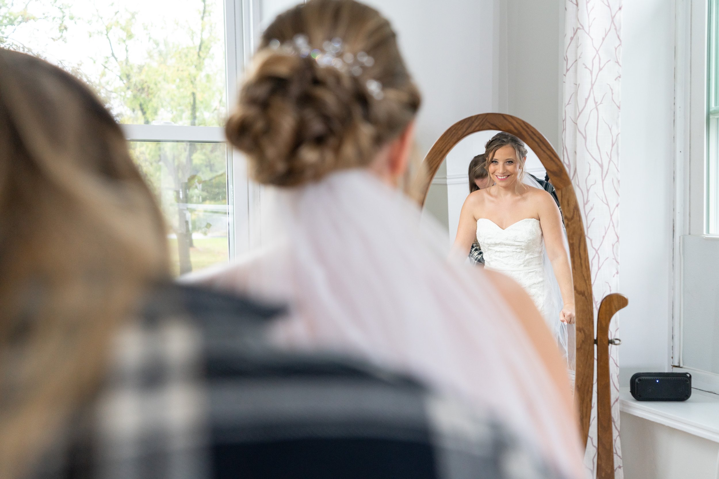 Bride looking at her reflection in mirror at Stover Hall bridal suite