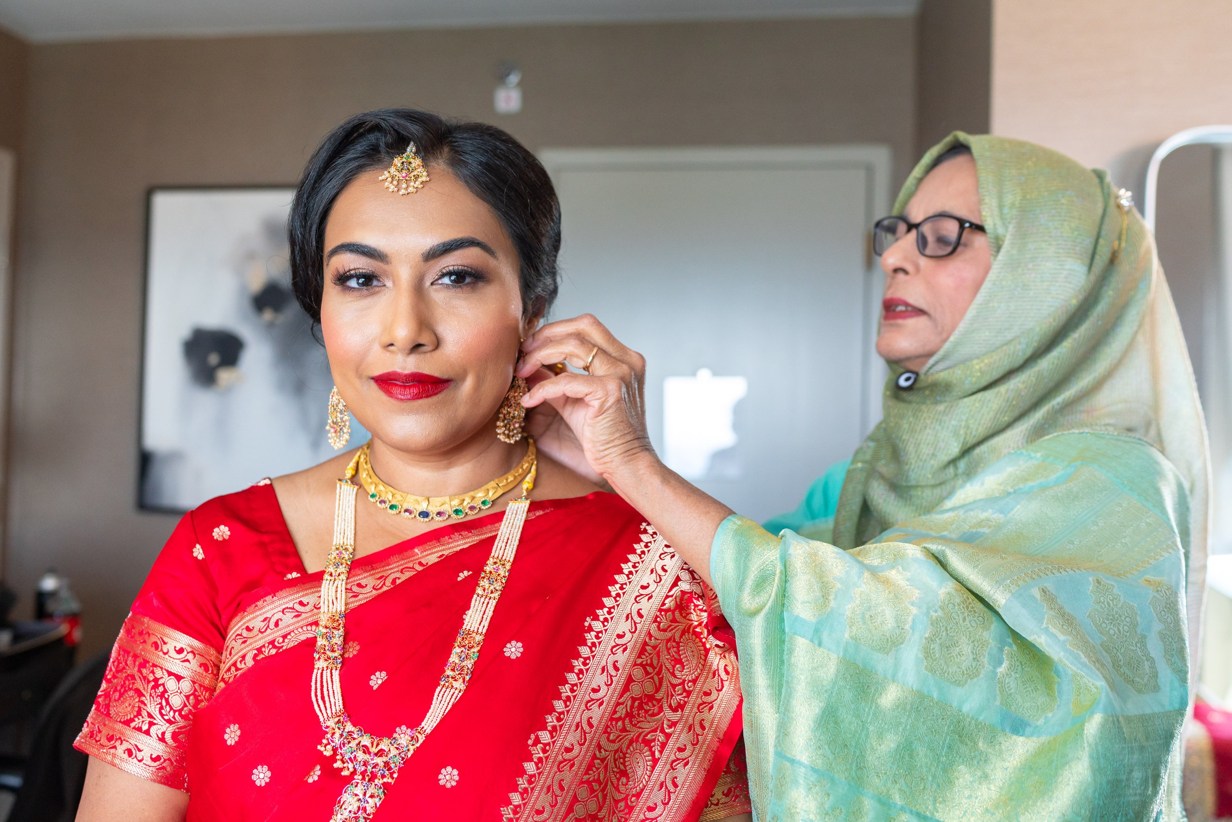 Aunt putting earrings on Indian bride at Hyatt regency Dulles in virginia