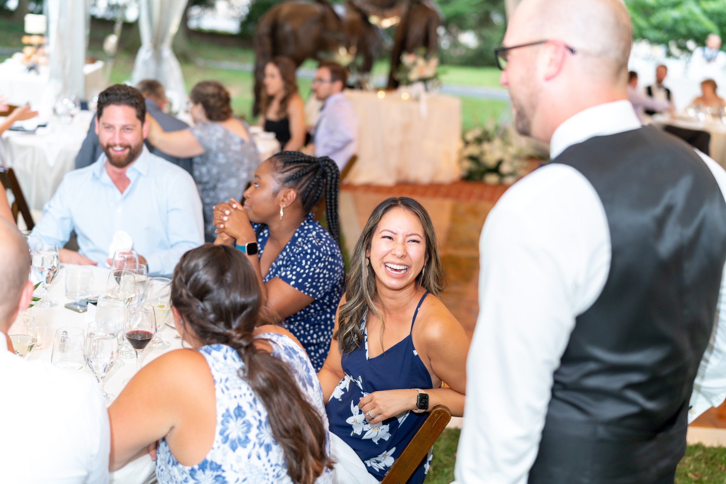 Guests laugh and smile as the groom greets them during fun wedding reception