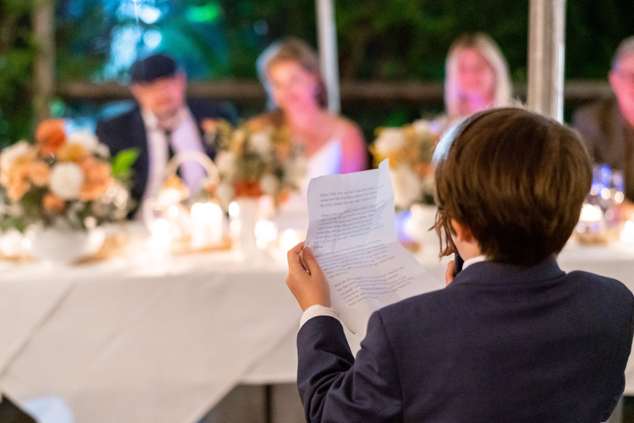 A boy reads his speech to his dad and new mom during the reception