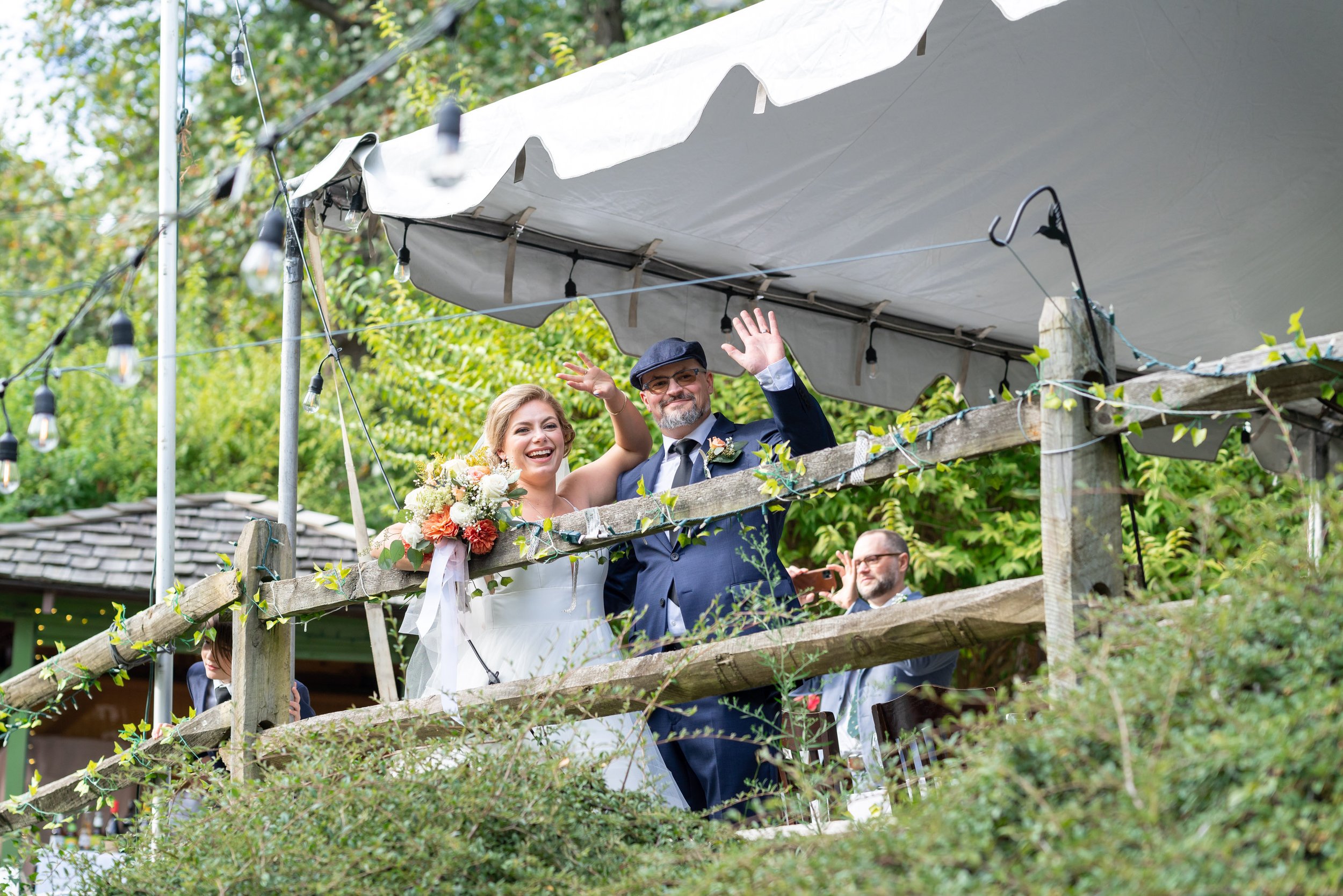 Bride and groom wave down to wedding guests at Old Angler's Inn