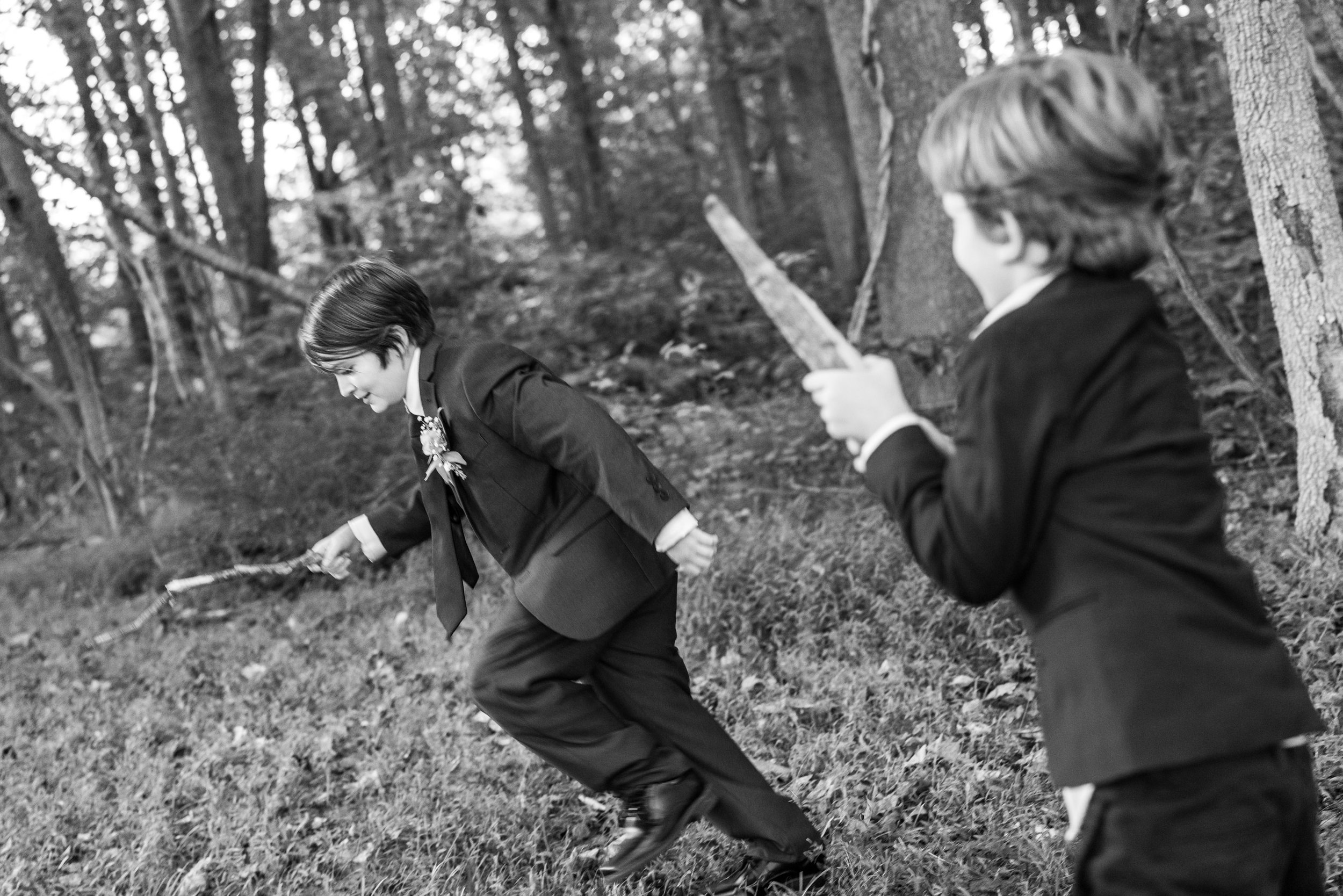 Two boys play swords with sticks in the woods behind Old Angler's Inn