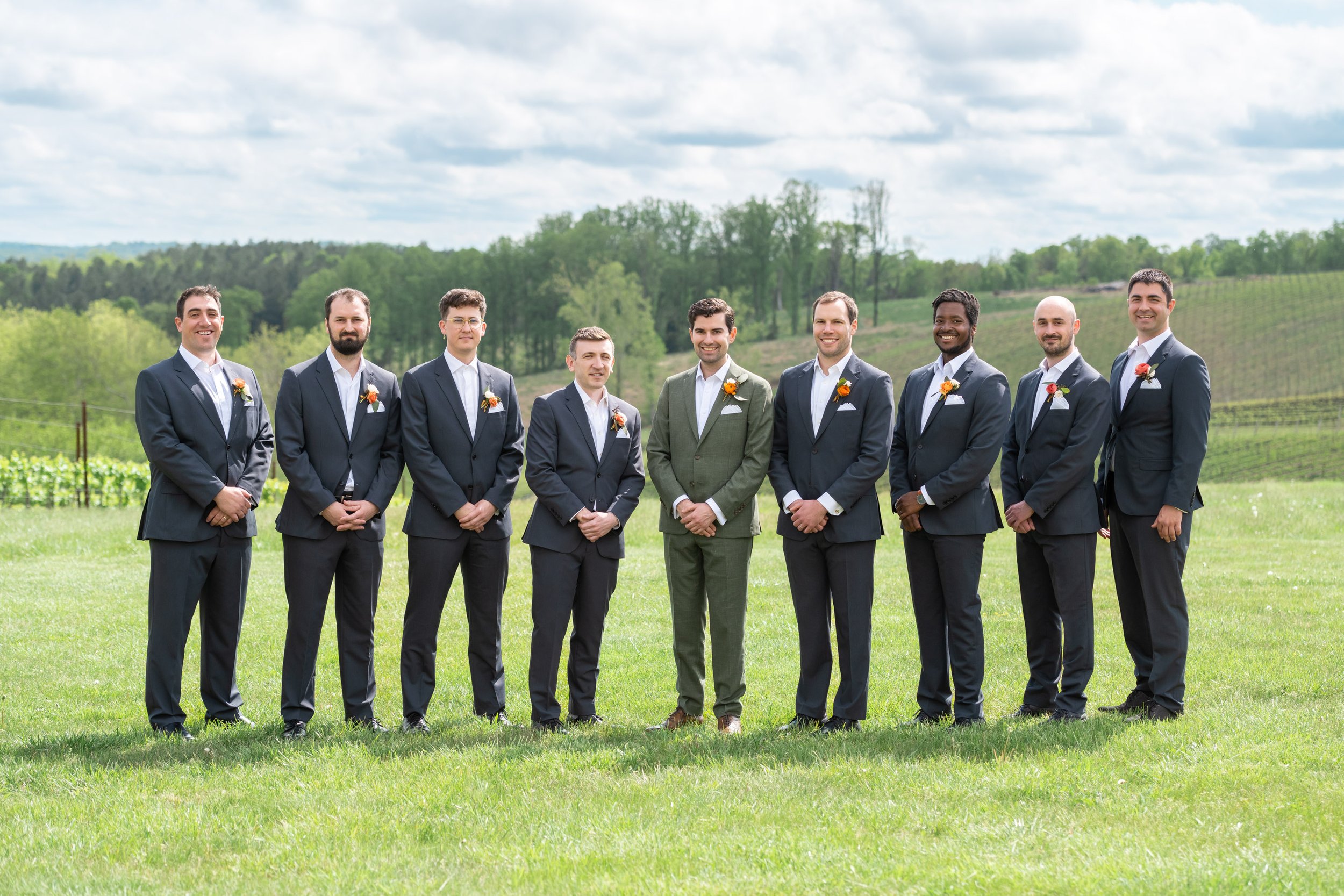 Groomsmen in black suits and groom in green linen suit at Stone Tower wedding