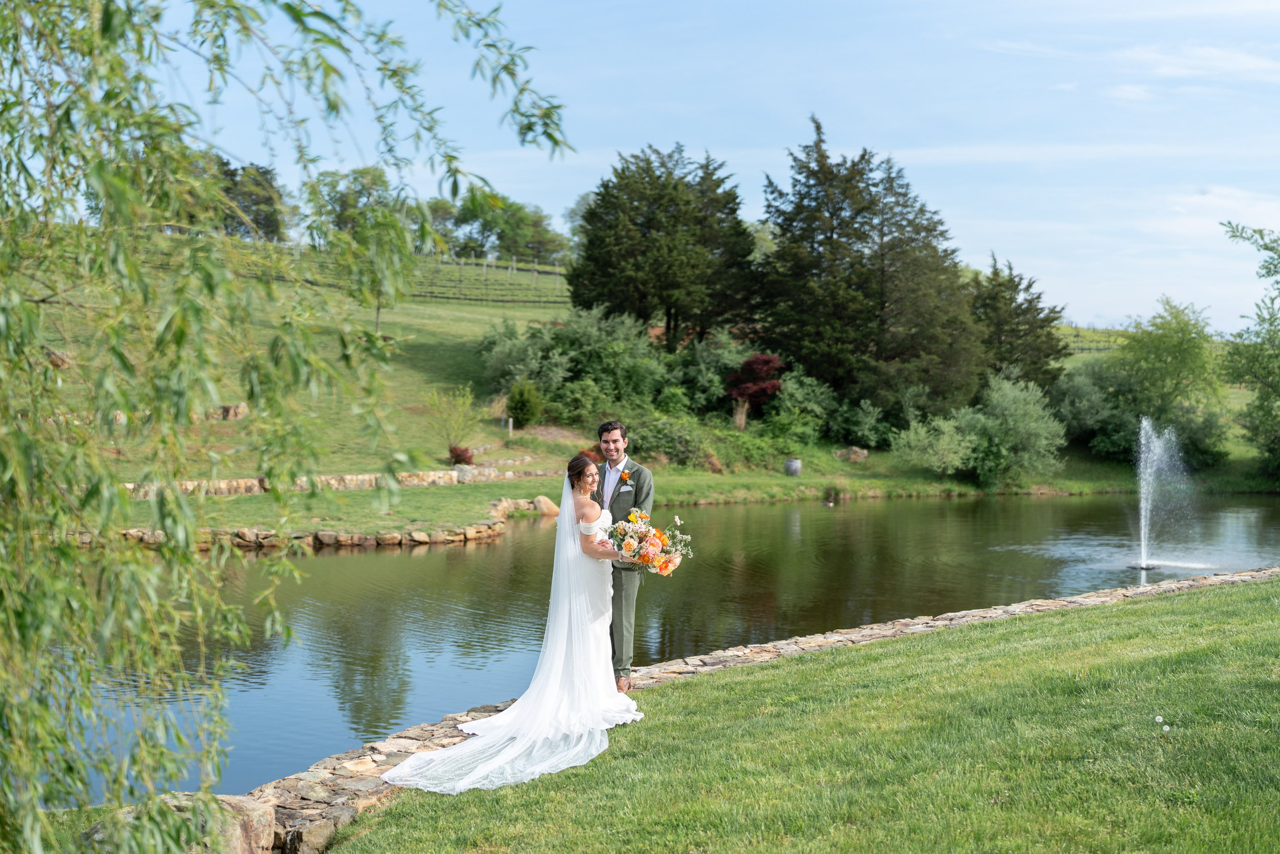 Bride and groom pose at the lake at Stone Tower Winery