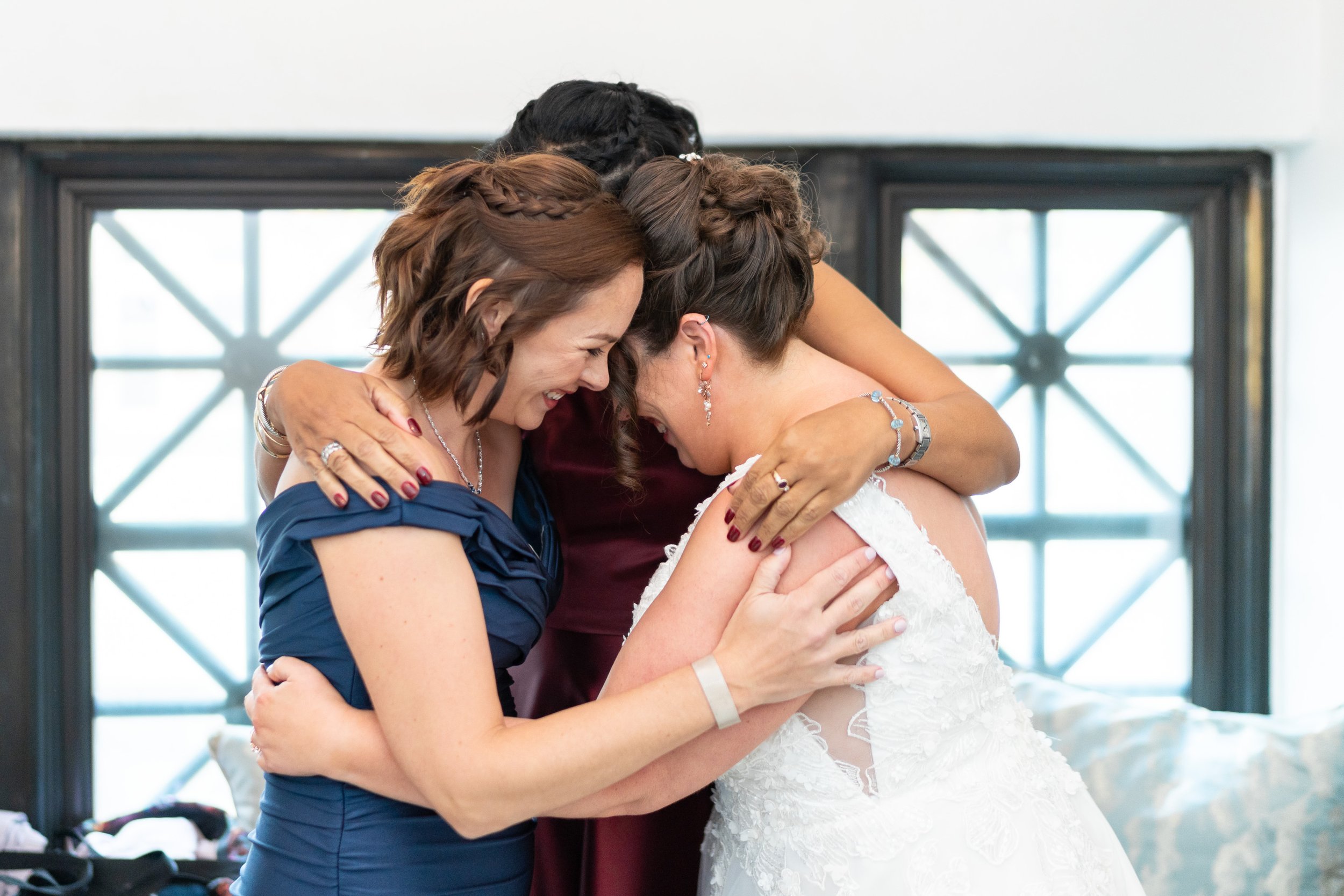 Bride and bridesmaids hug in getting ready suite at citizens ballroom bank