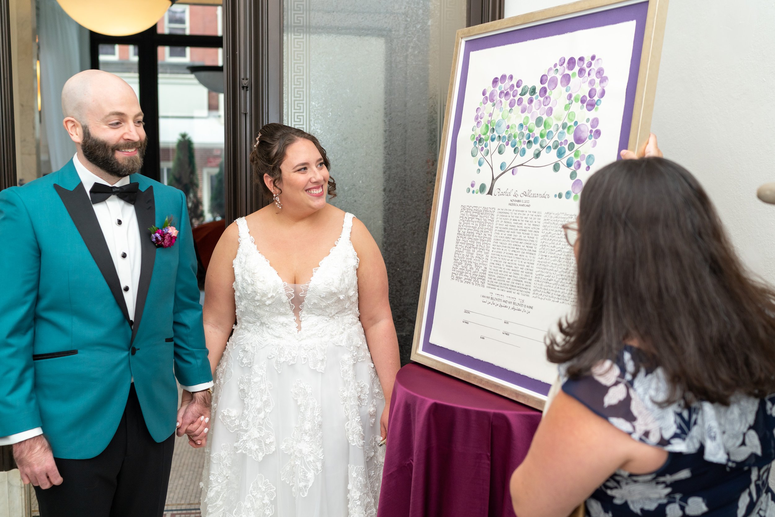 Bride and groom look at ketubah at citizen's ballroom fun wedding in Frederick md