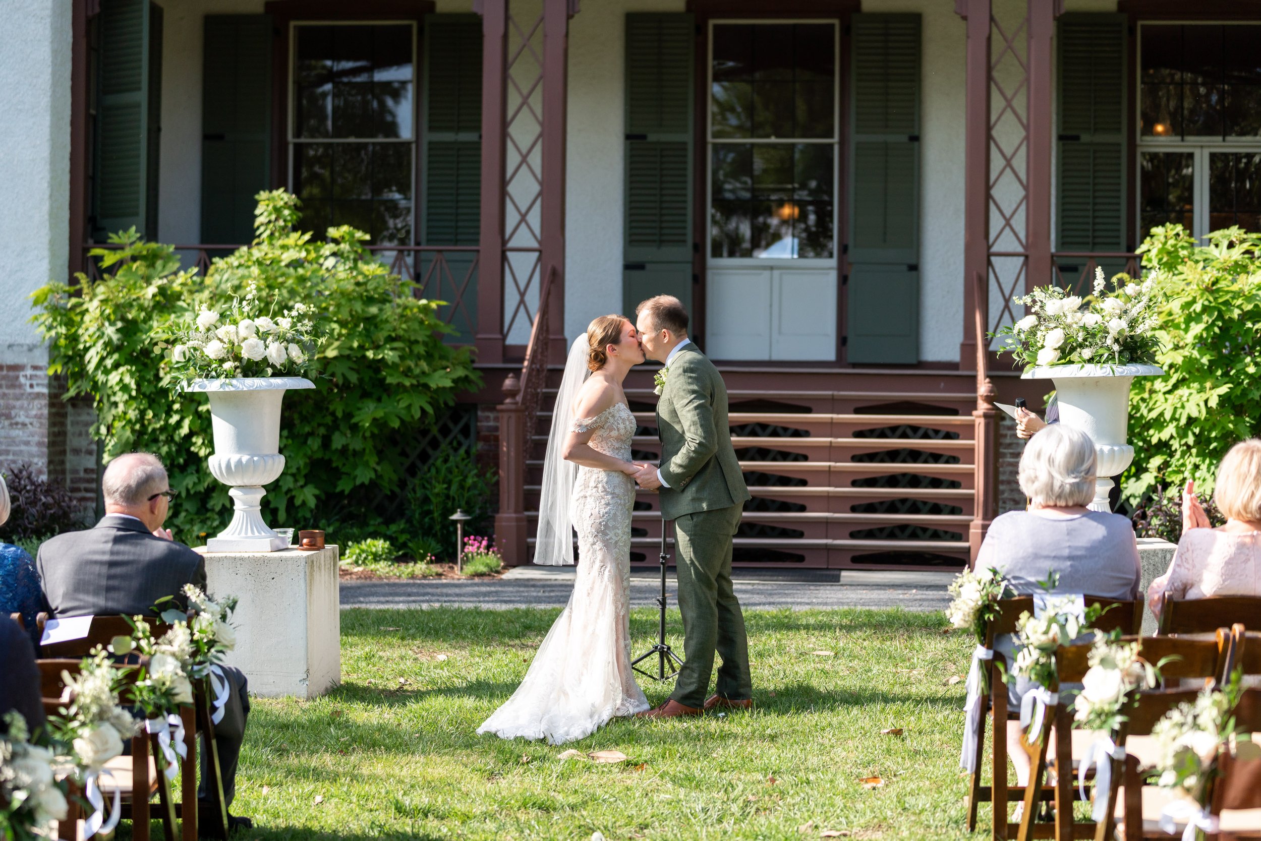 Bride and groom kiss in front of Lincoln's Cottage on the lawn in DC