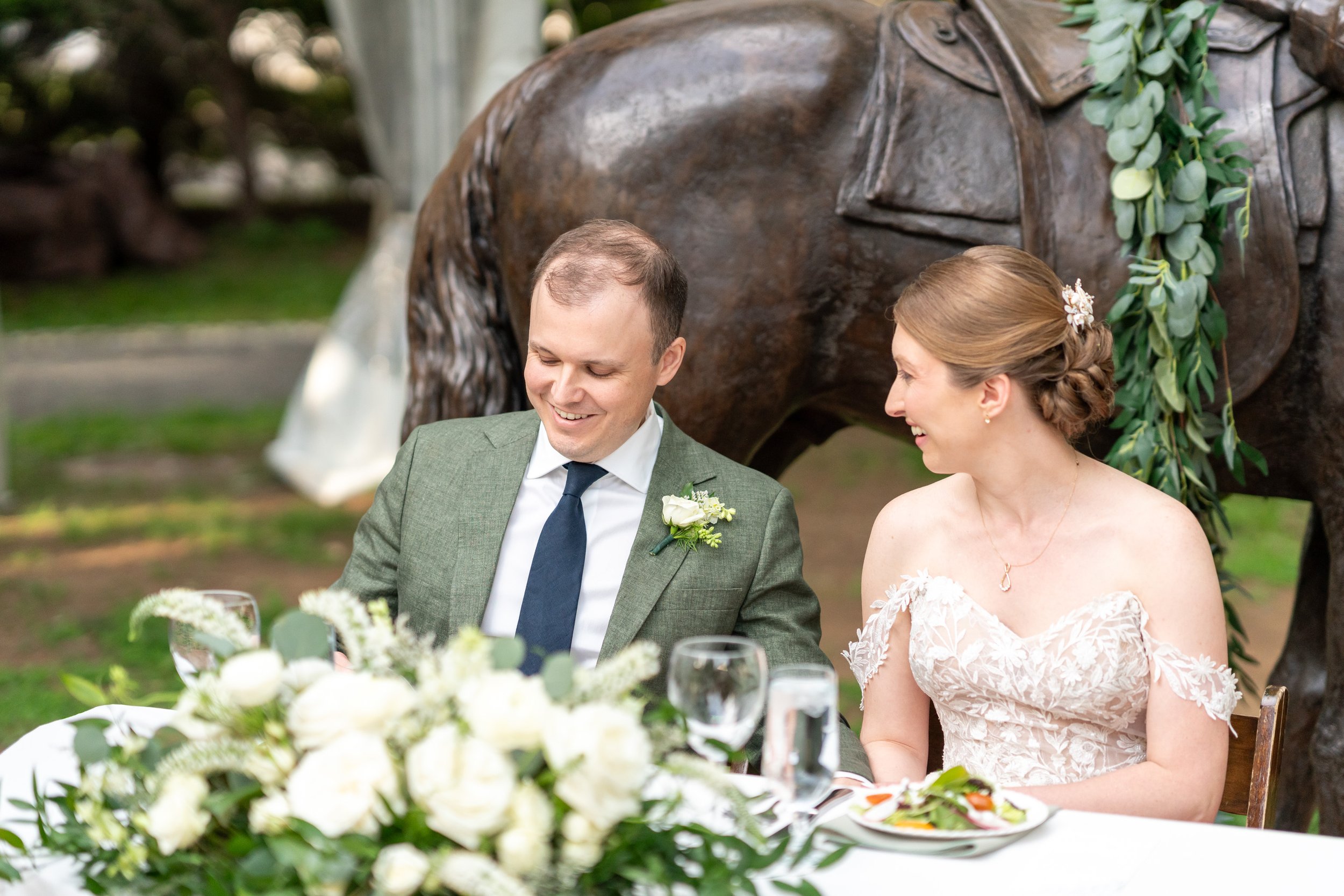 bride and groom sit in front of Lincoln statue with horse at Lincoln's Cottage