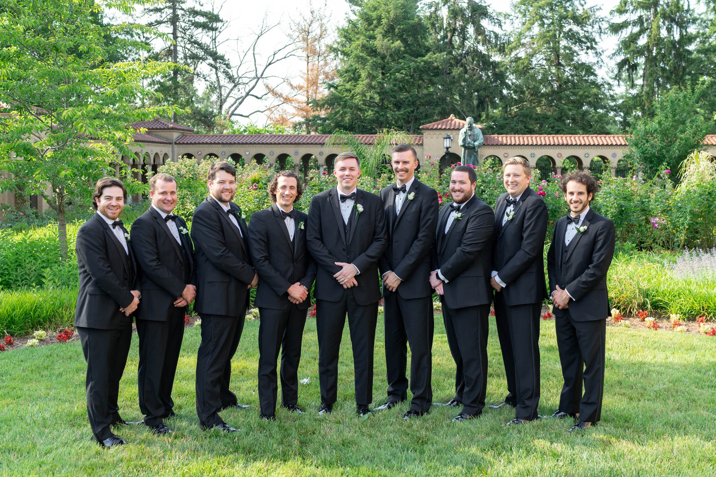 Groomsmen in tuxedos in garden St Francis Hall Monastery in summer June wedding photos