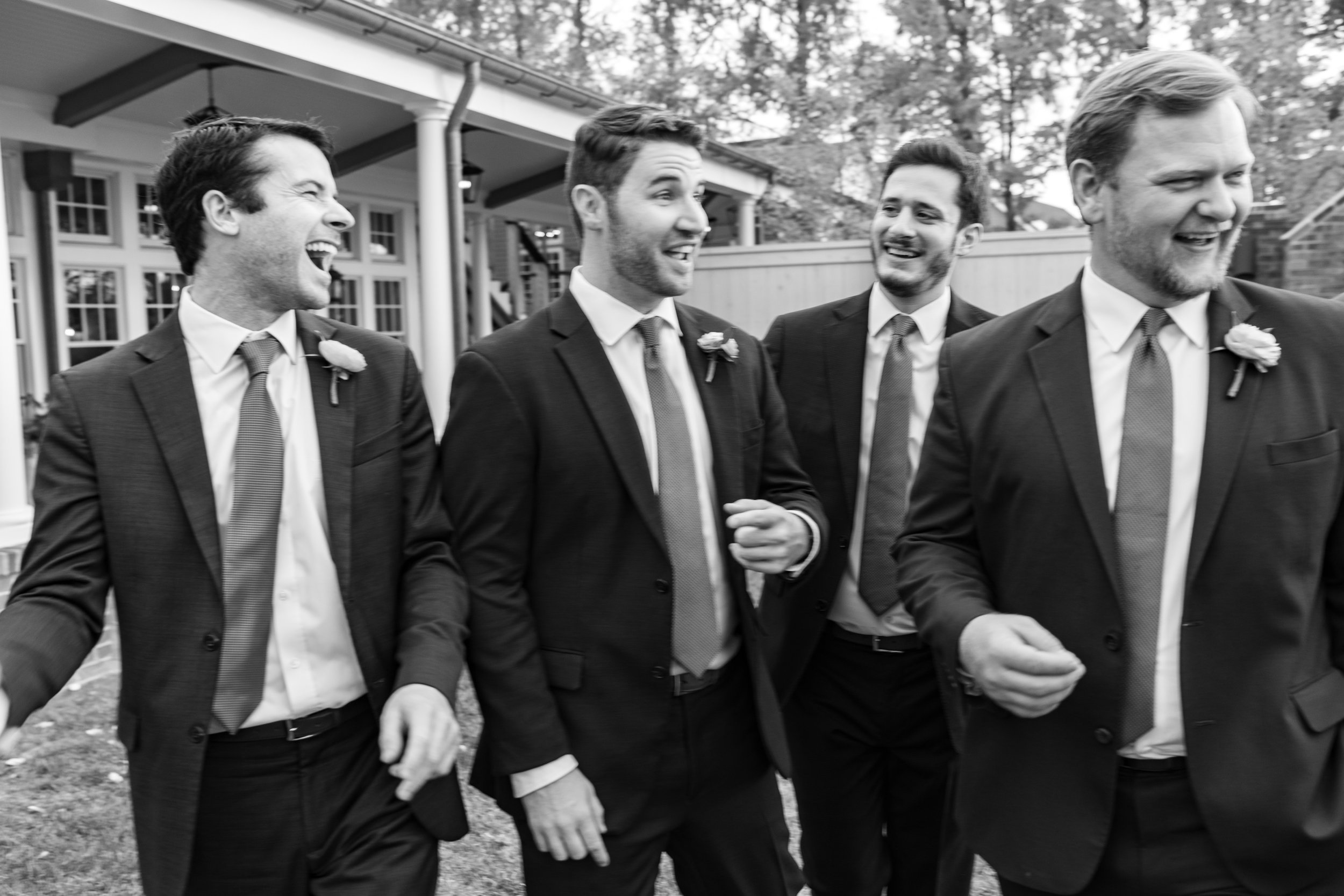 black and white film style image of groomsmen walking and laughing candid