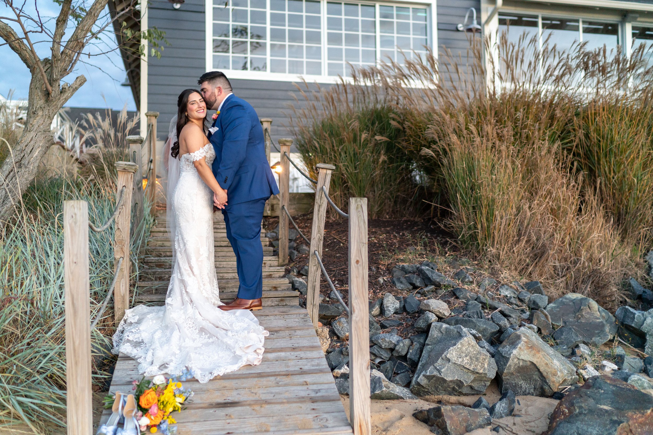 bride and groom on wooden bride in front of Chesapeake Bay Beach Club on the beach