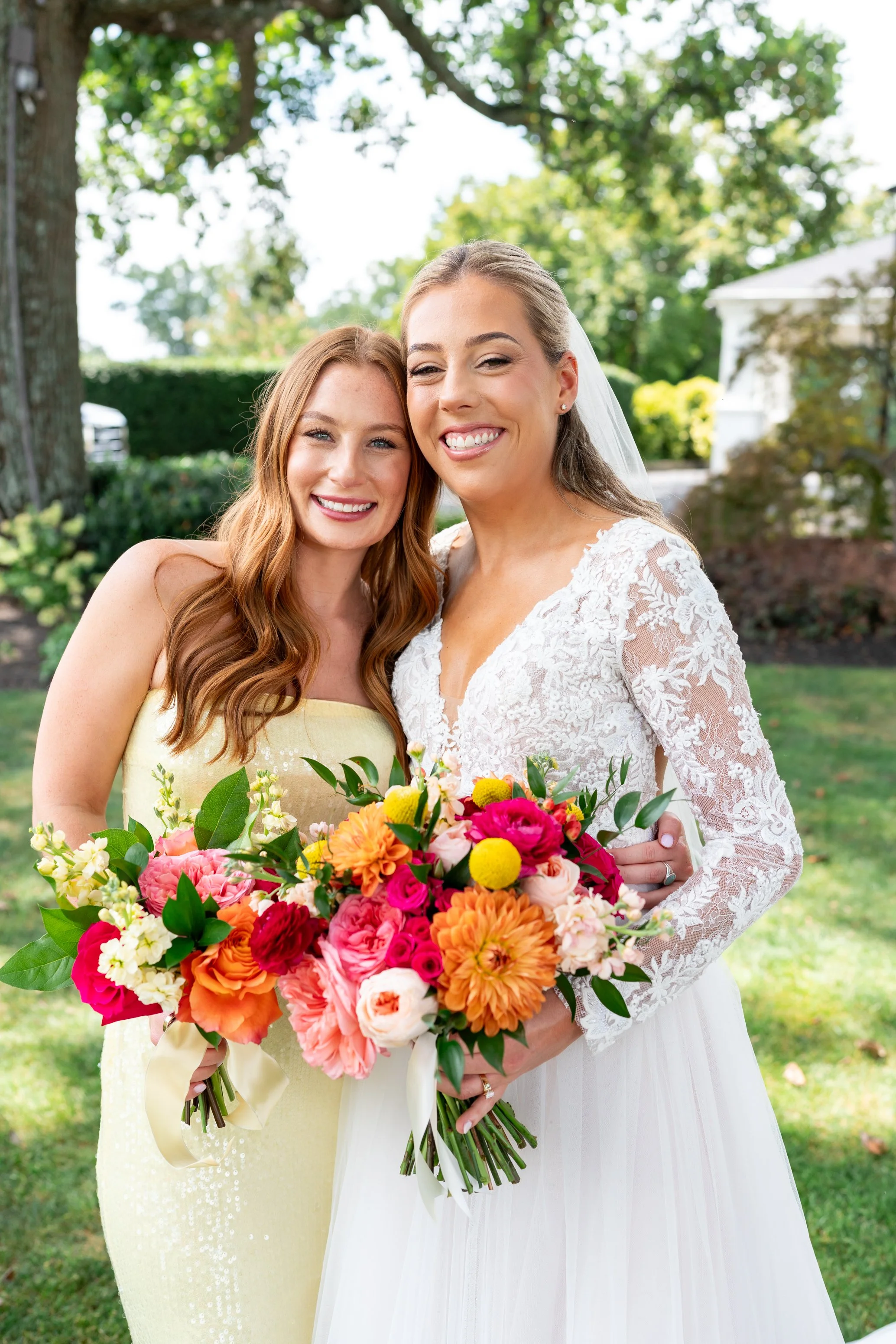 Bridesmaid with bride in yellow sequin endless rose dress with sunset color flowers