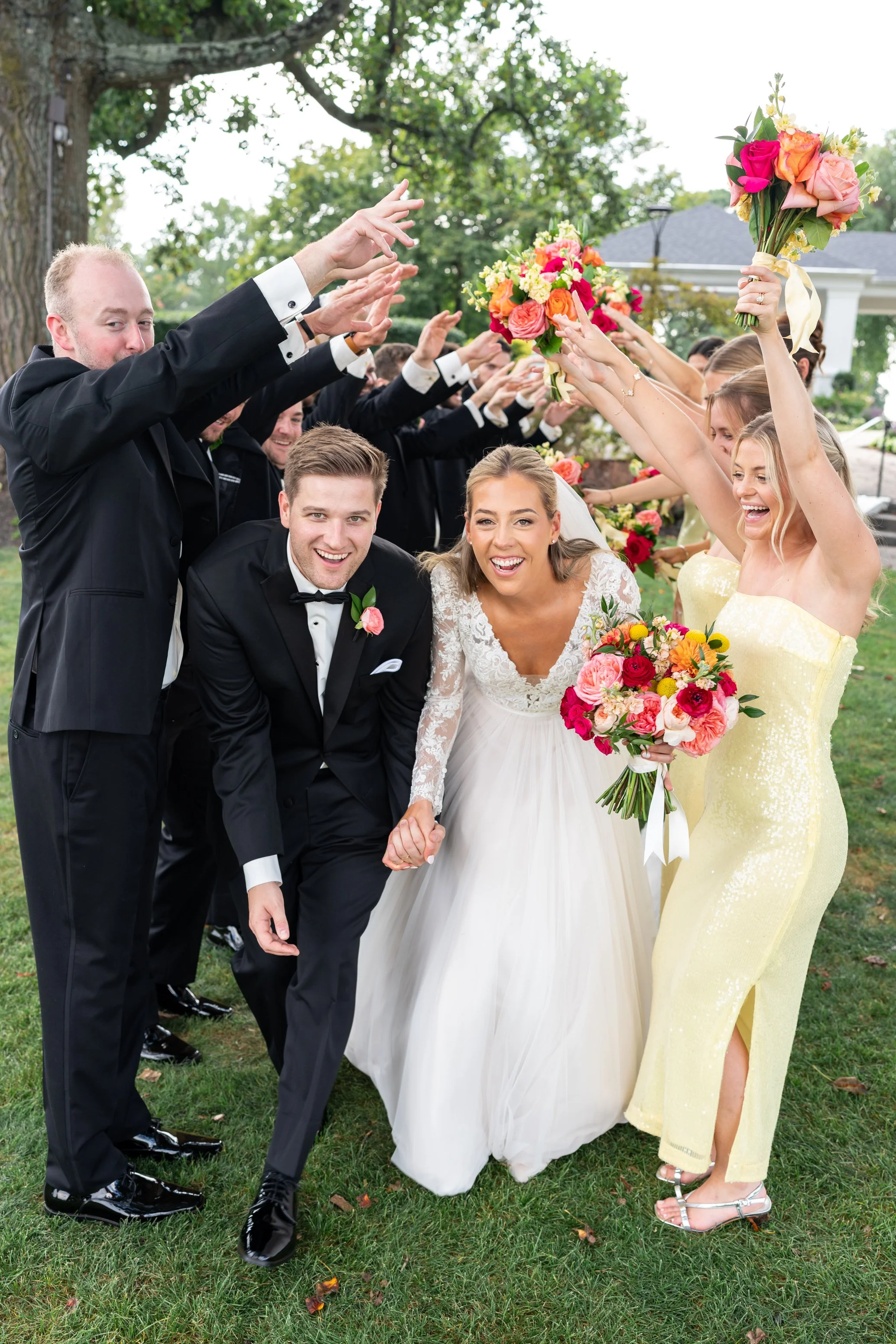Bride and groom running under hands tunnel from wedding party at Manor country club