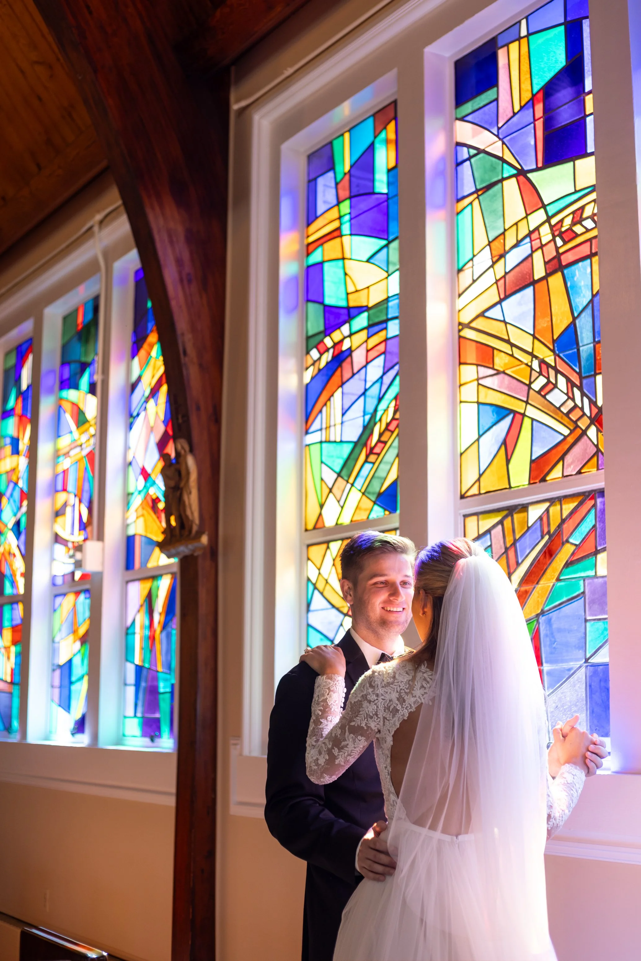 Bride and groom dance in stained glass light at St Patrick's Catholic Church in Rockville Maryland wedding